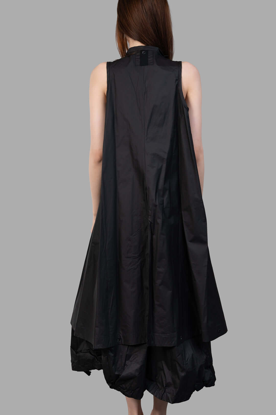 Masnada 2-in-1 Parka back view on-model, sleeveless black parka with flowing A-line shape and layered hem.