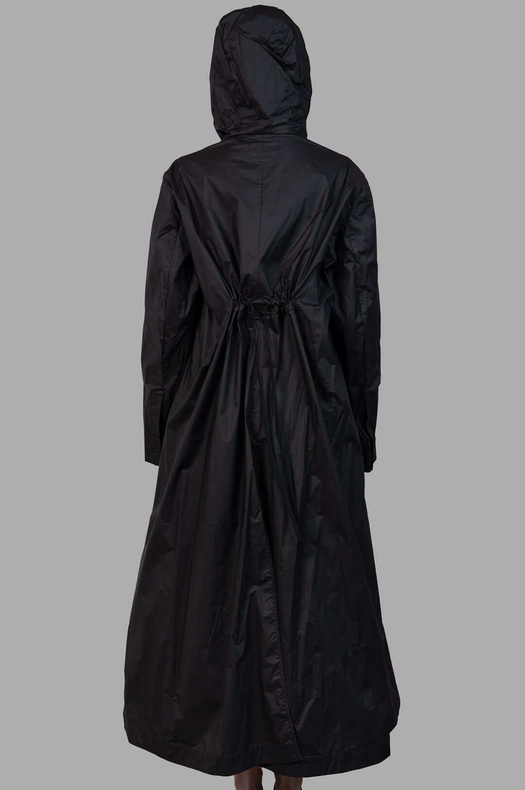 Masnada 2-in-1 Parka back view on-model, black long hooded coat with drawstring waist and draped hem.