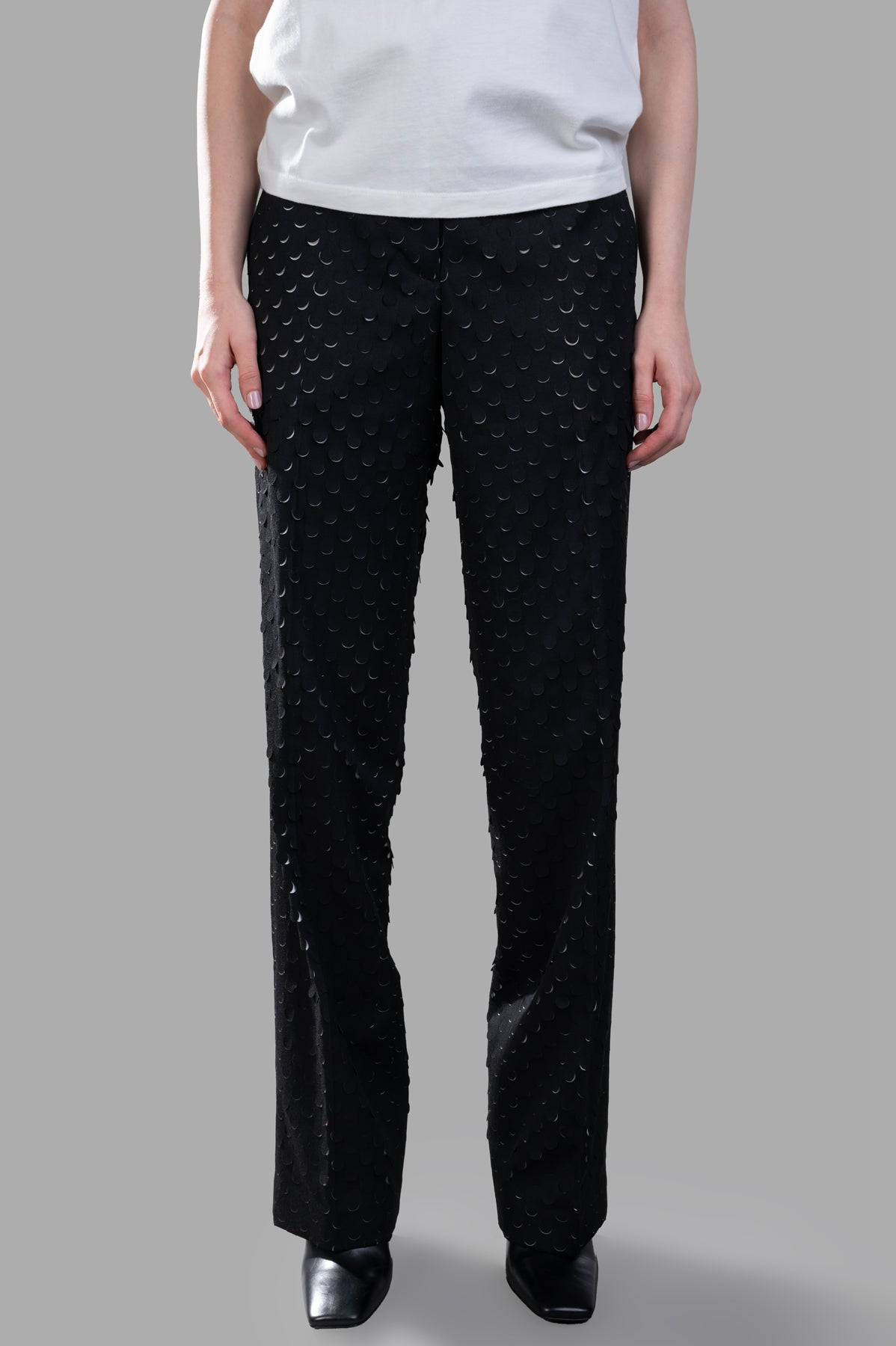 Helmut Lang Hole-Punched Car Trousers in black, featuring a textured surface, relaxed fit, and low-rise waist on model.