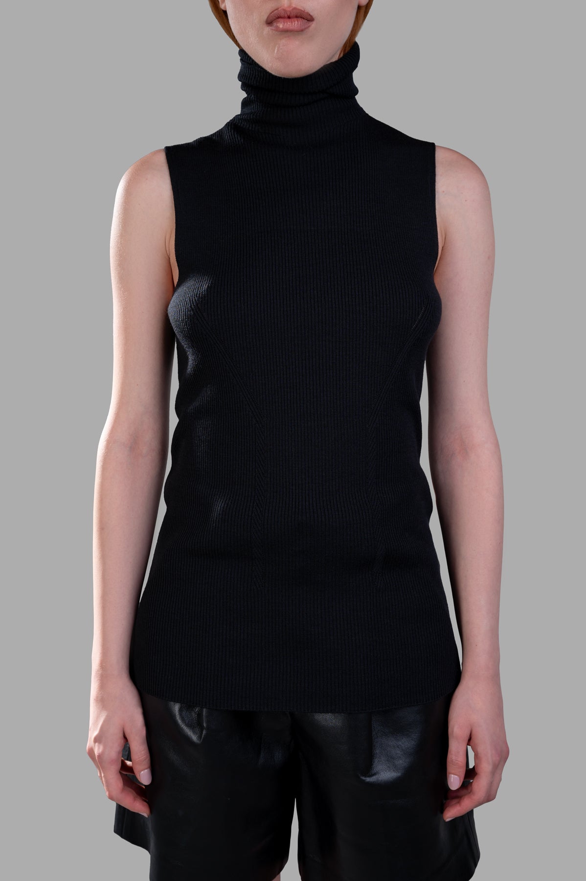 Gentry Portofino sleeveless sweater in black, featuring a ribbed knit texture and turtleneck, shown on a model.