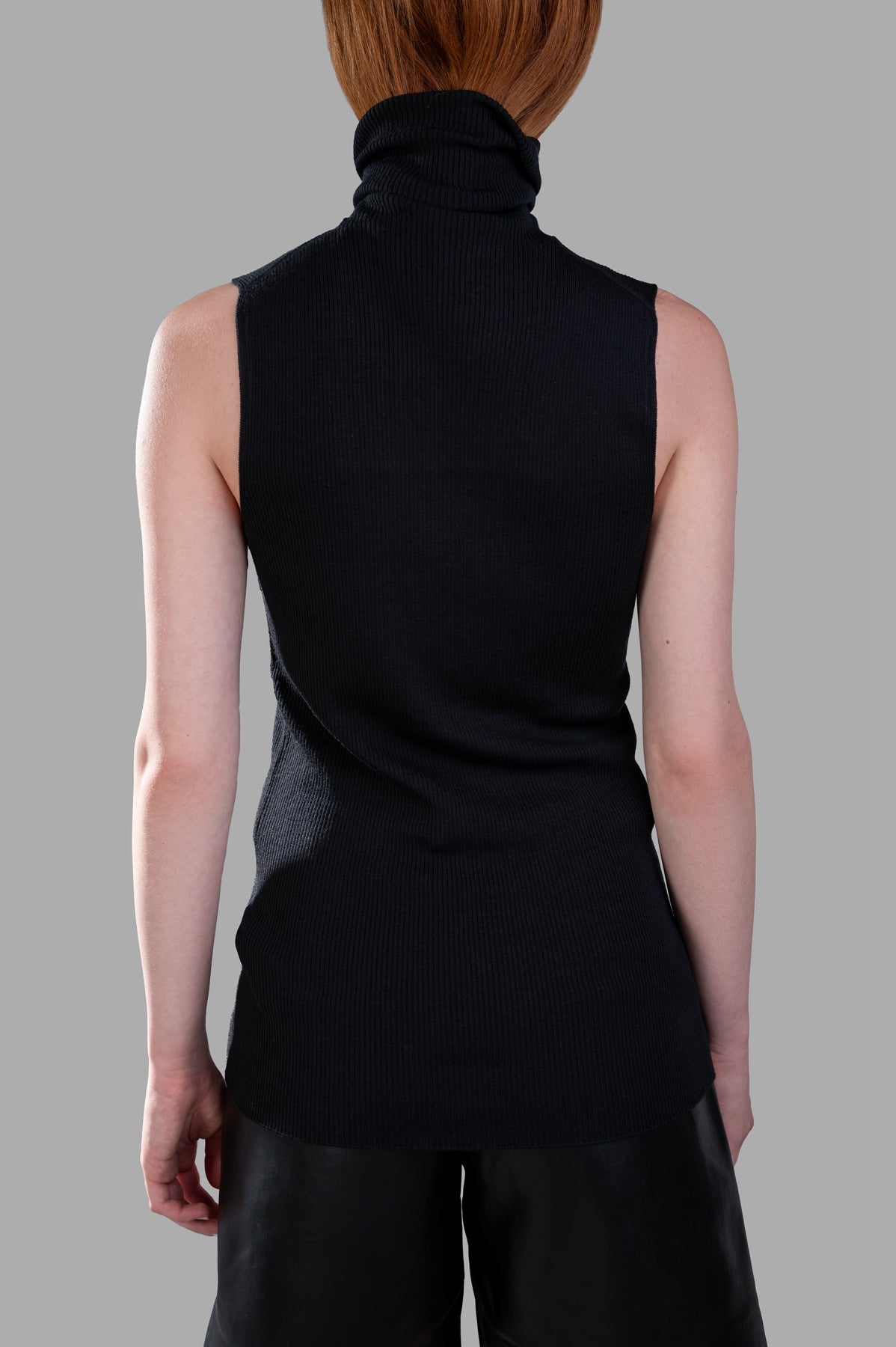 Gentry Portofino sleeveless sweater showcased from the side, highlighting its elegant turtleneck and ribbed details in black.