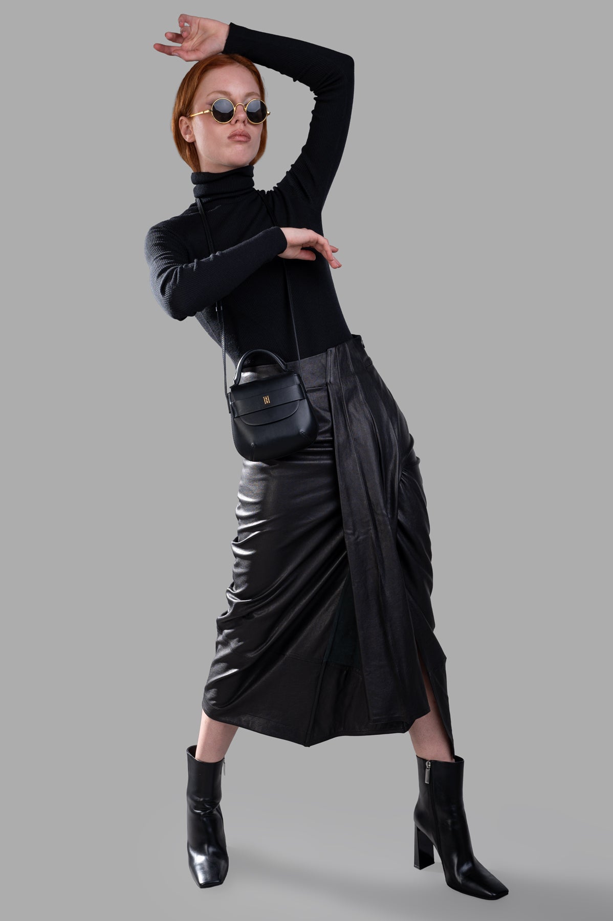 Gentry Portofino Leather Pencil Skirt in black, front view on model, showing asymmetric pleating and high waist design.