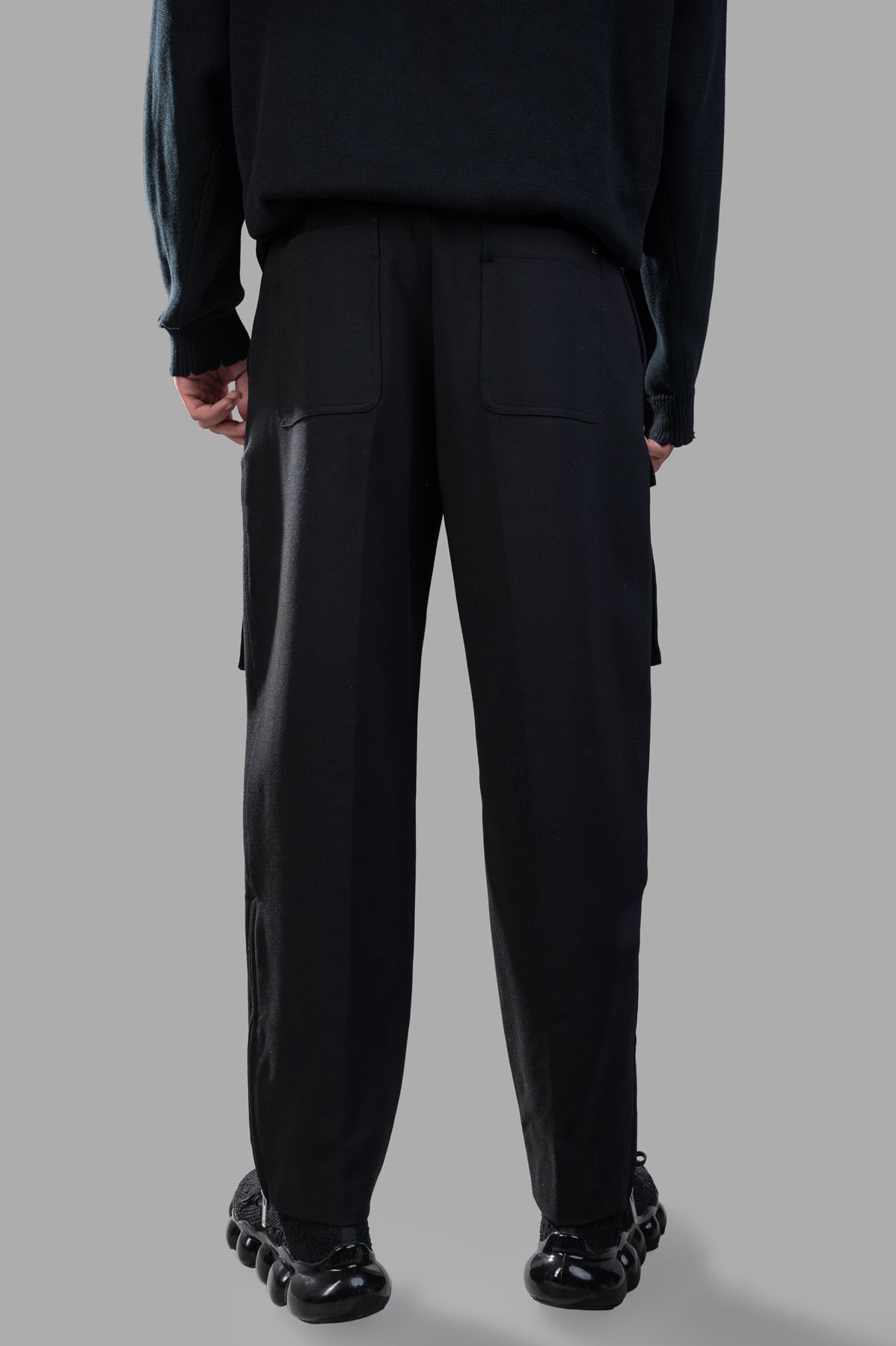 Helmut Lang Pocket Zoot Pants shown from the back, featuring utilitarian flap pockets and relaxed carrot shape in black.