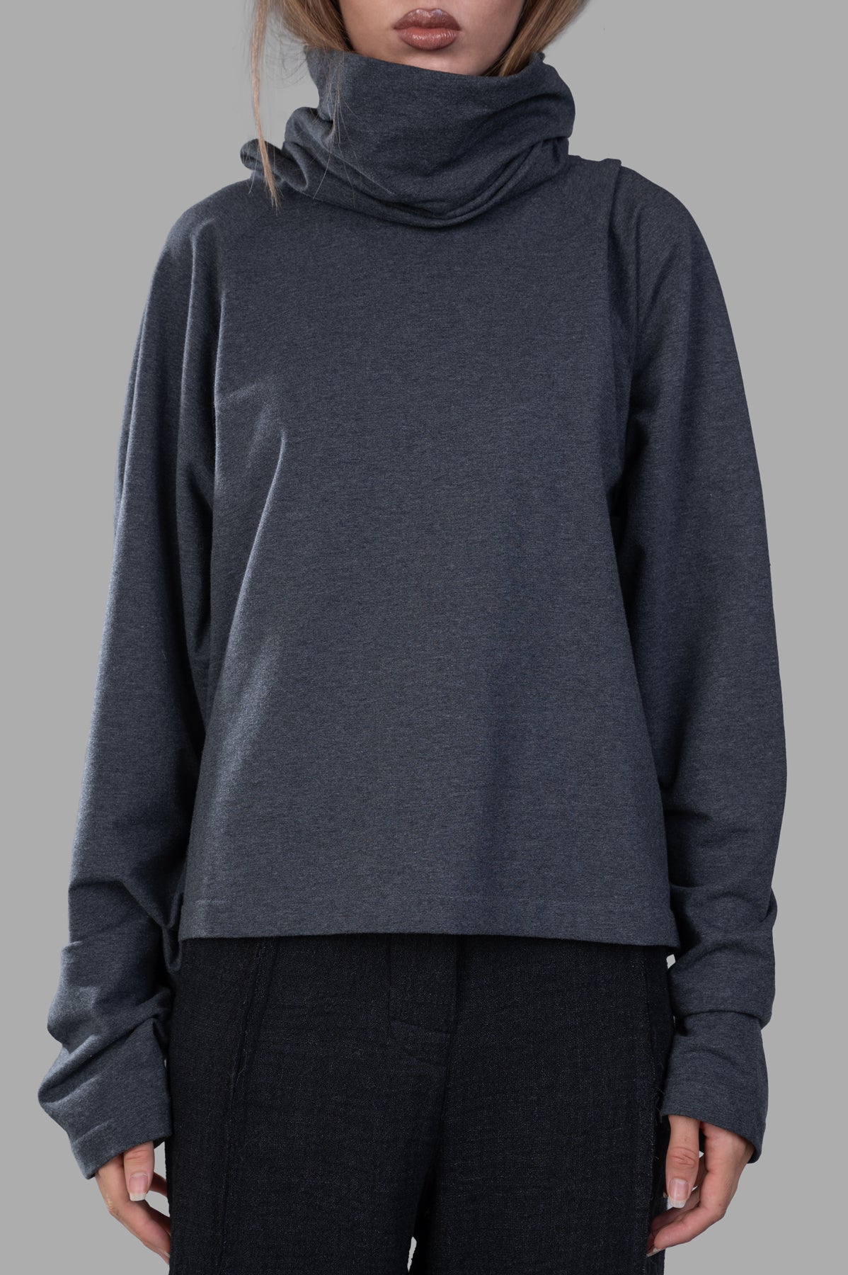 Norma Kamali Raglan-Sleeve Turtleneck Top in grey, featuring an elegant hood and relaxed fit, displayed on a model.