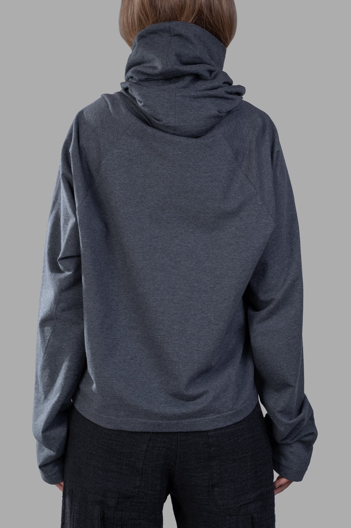 Norma Kamali Raglan-Sleeve Turtleneck Top featuring a versatile hood and relaxed fit, shown in grey with long sleeves.