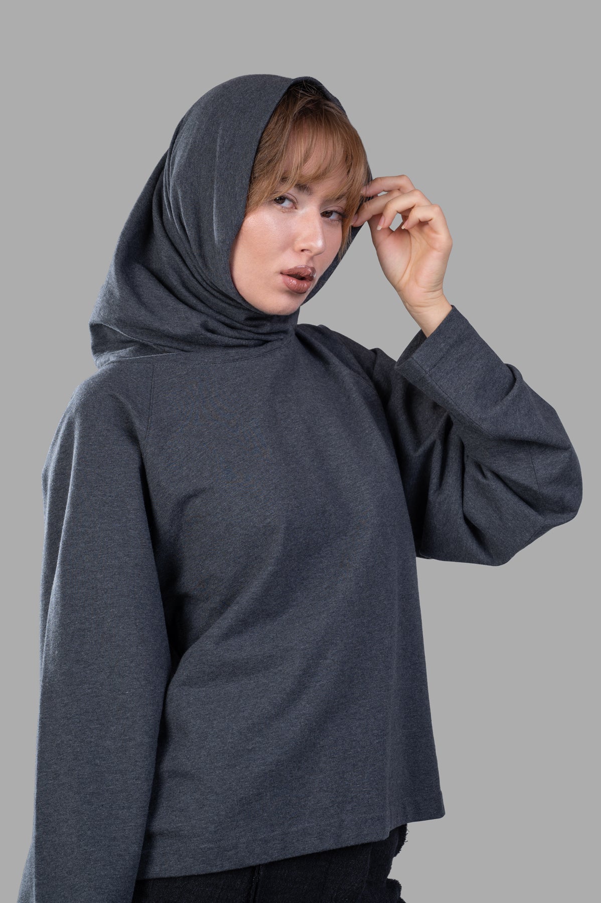 Norma Kamali Raglan-Sleeve Turtleneck Top in grey features a relaxed fit, hood, and oversized sleeves on a model.