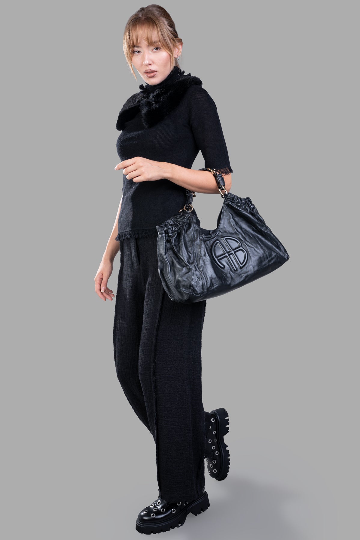Marc Point Textured Trousers in black, model wearing high-waisted, wide-leg design with pleats, side view.