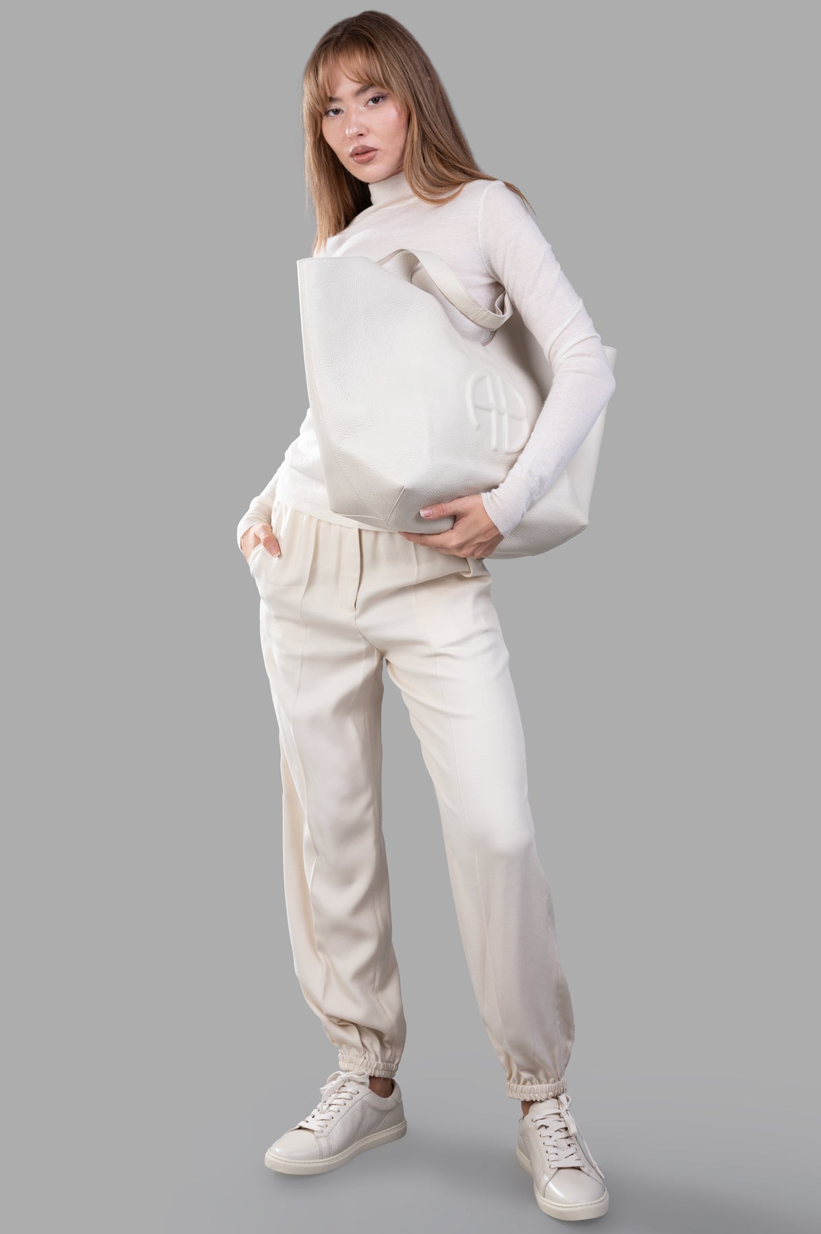 Joseph Cashair High-neck Jumper, front view on-model, paired with light pants, holding a large white bag.