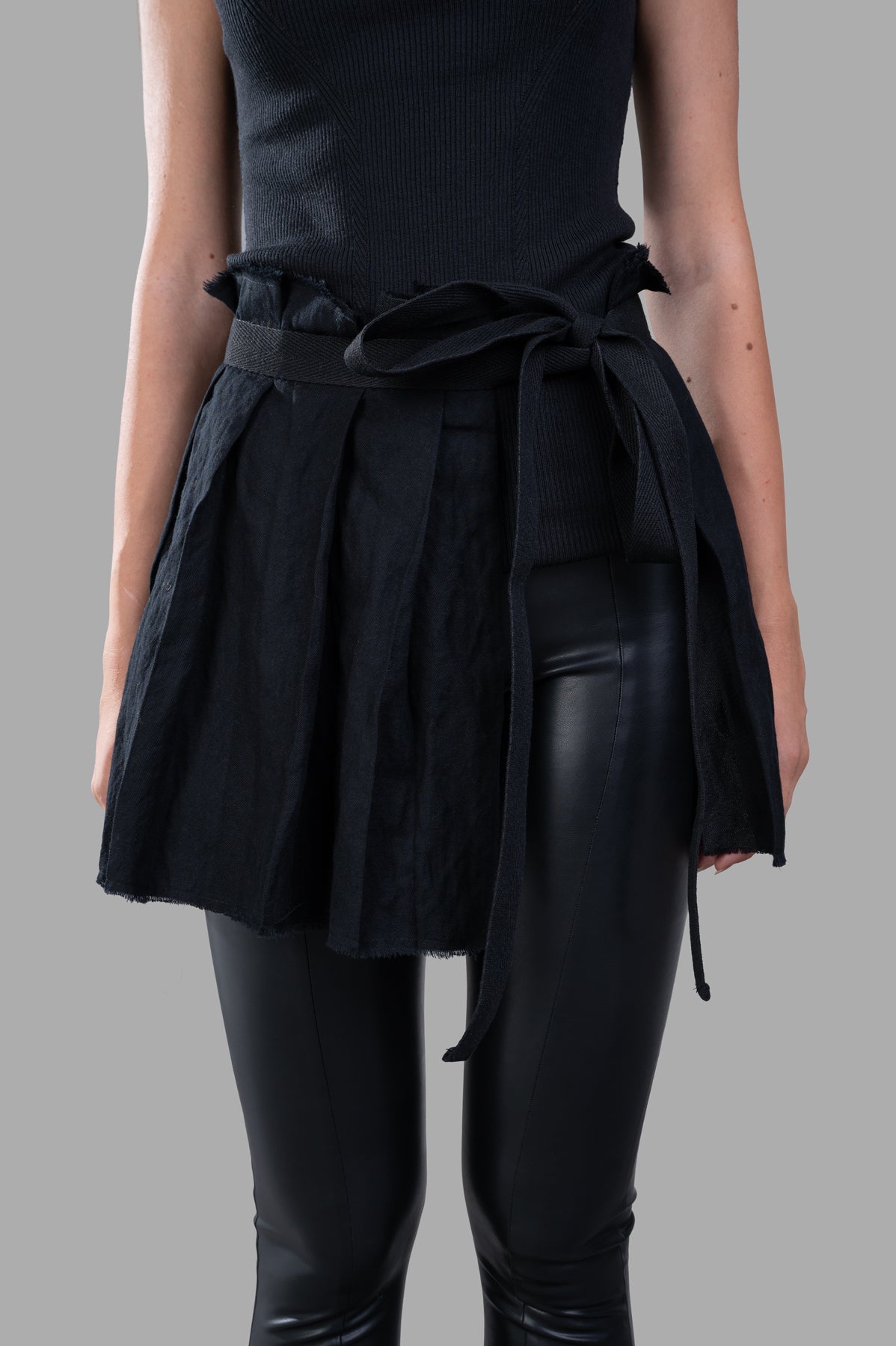 Masnada Self-tie Skirt in black showcases bold pleats and adjustable tie, perfect for layering with any outfit.