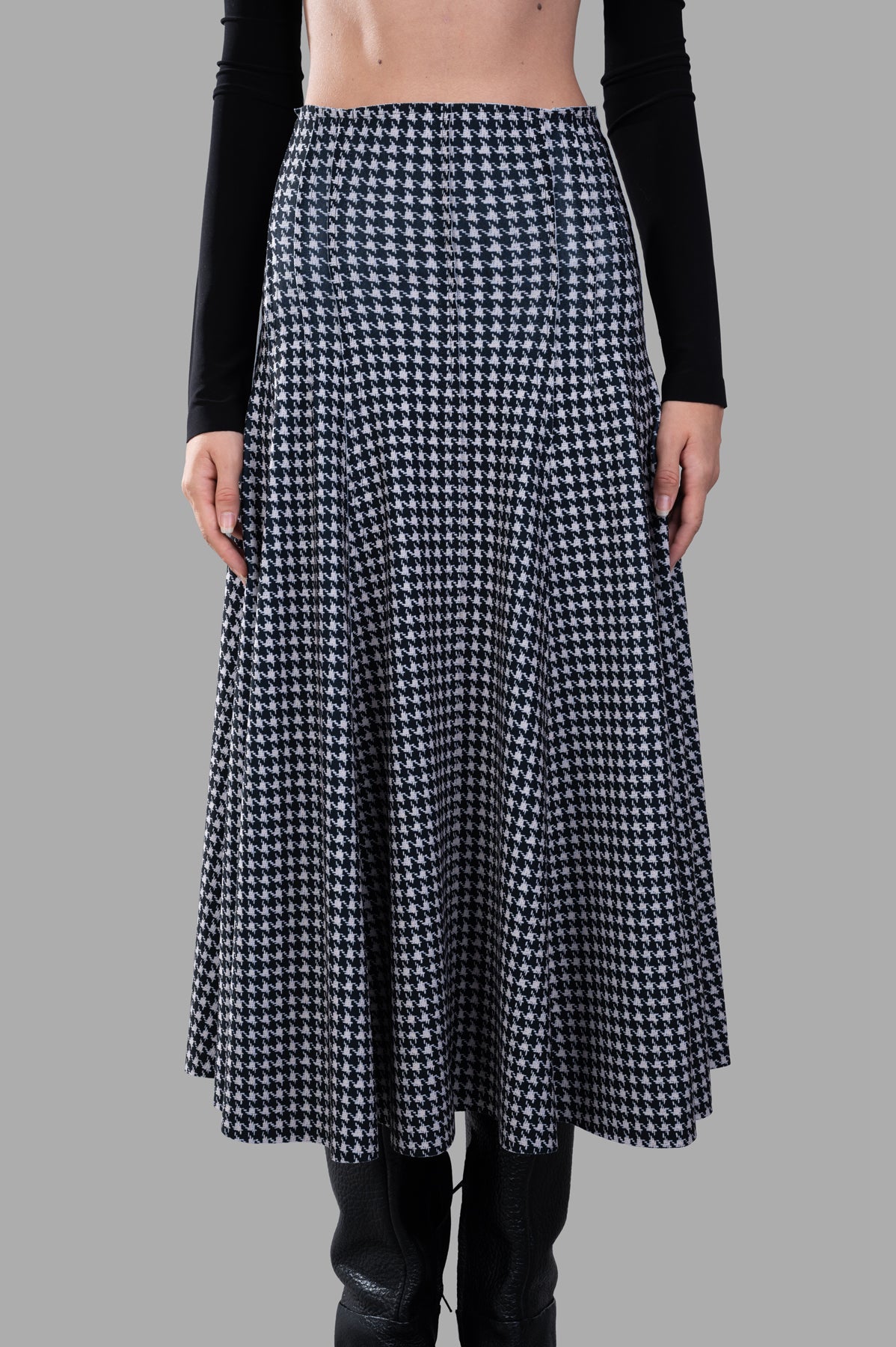 Norma Kamali Grace Houndstooth Skirt featuring a high waist and light pleats, displayed on a model against a gray background.