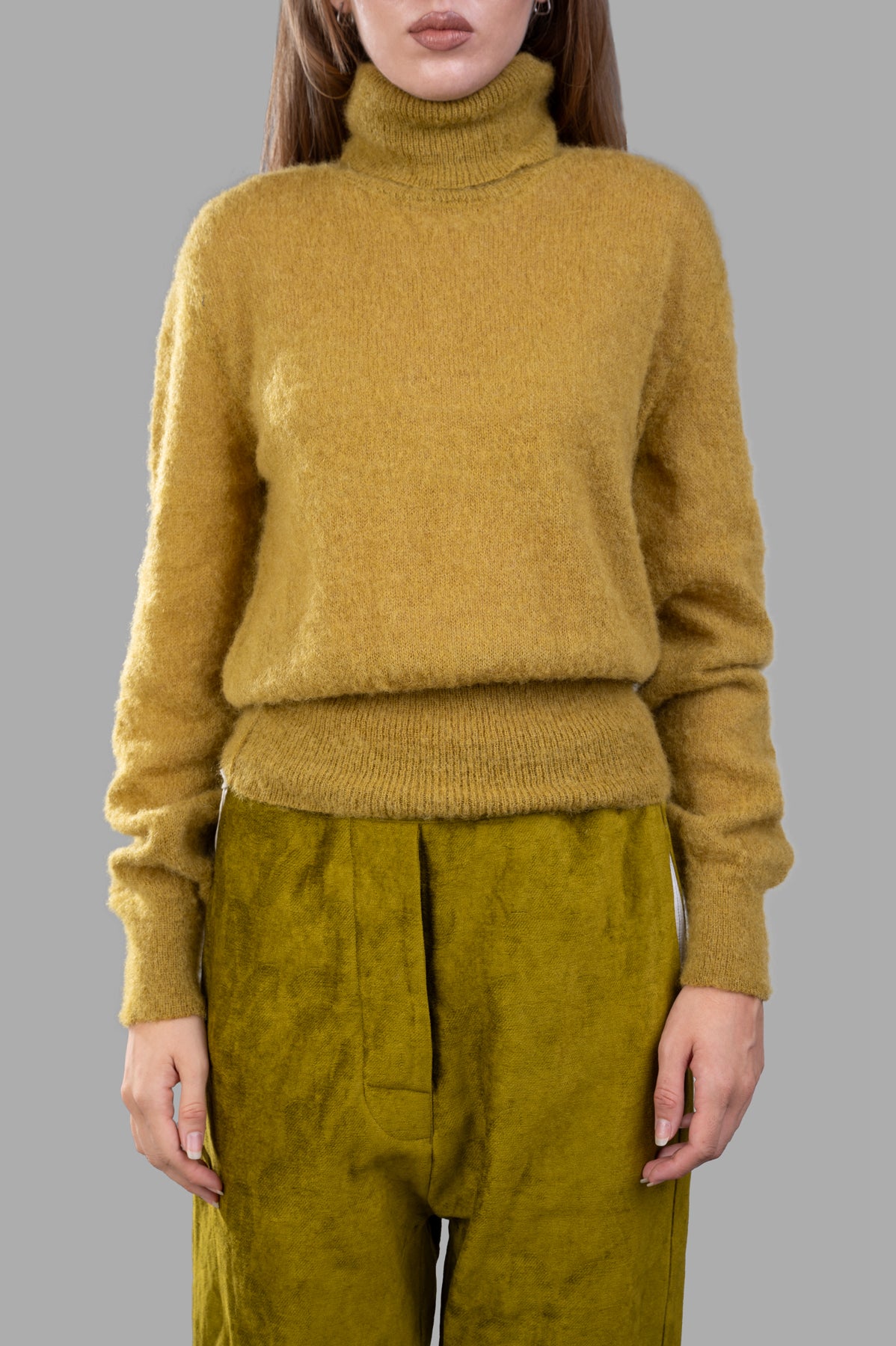 Marc Point Turtleneck Sweater in ochre, featuring a soft texture and ribbed hem, worn with stylish green pants.