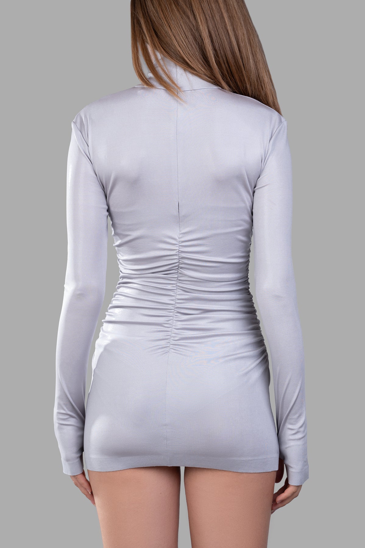 Norma Kamali Draped Mini Dress in silver, showcasing back view with ruched detailing and long sleeves.