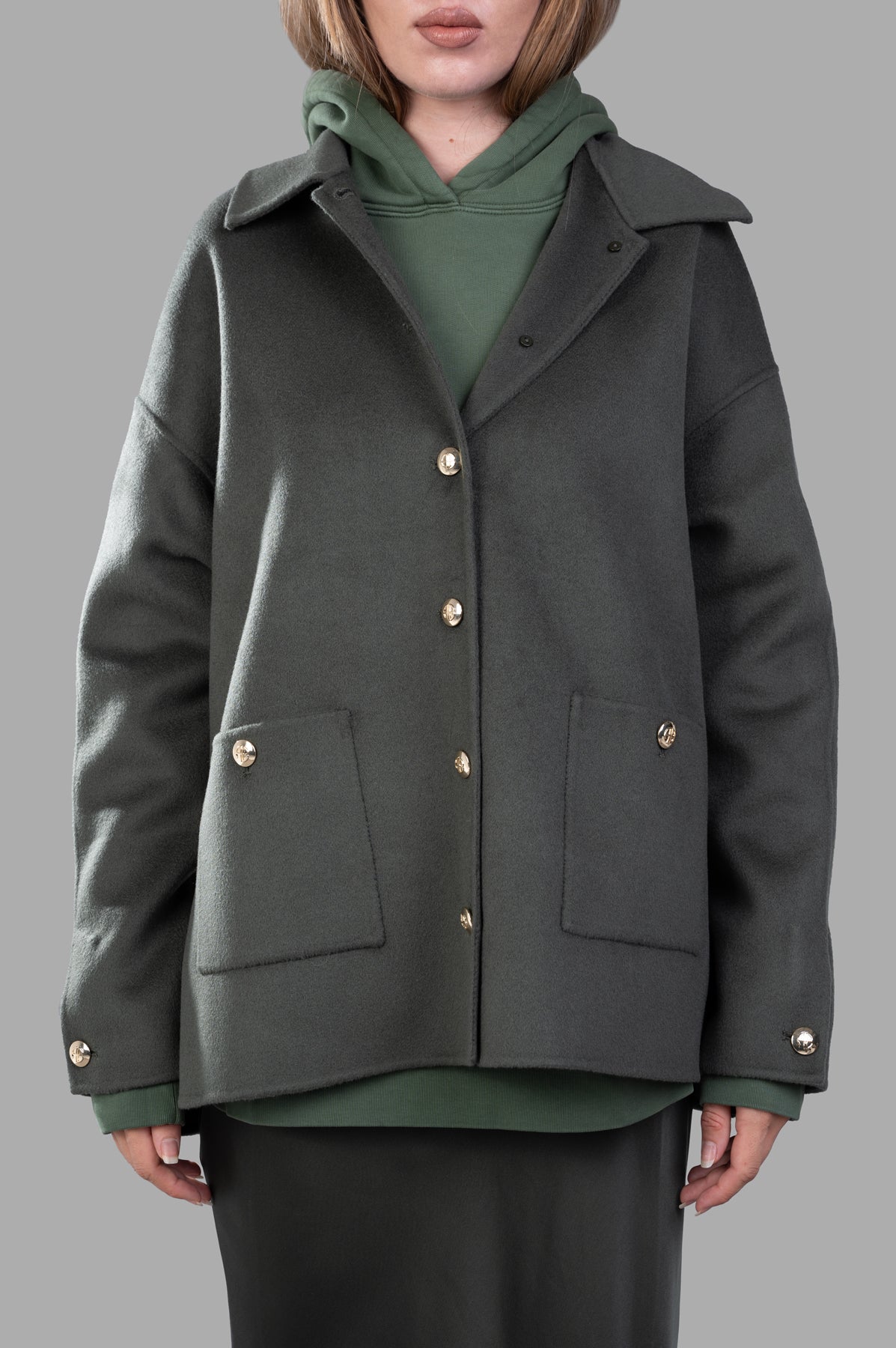 Anine Bing Luca Oversized Jacket in olive, showcasing front view with gold buttons and patch pockets, layered over a hoodie.