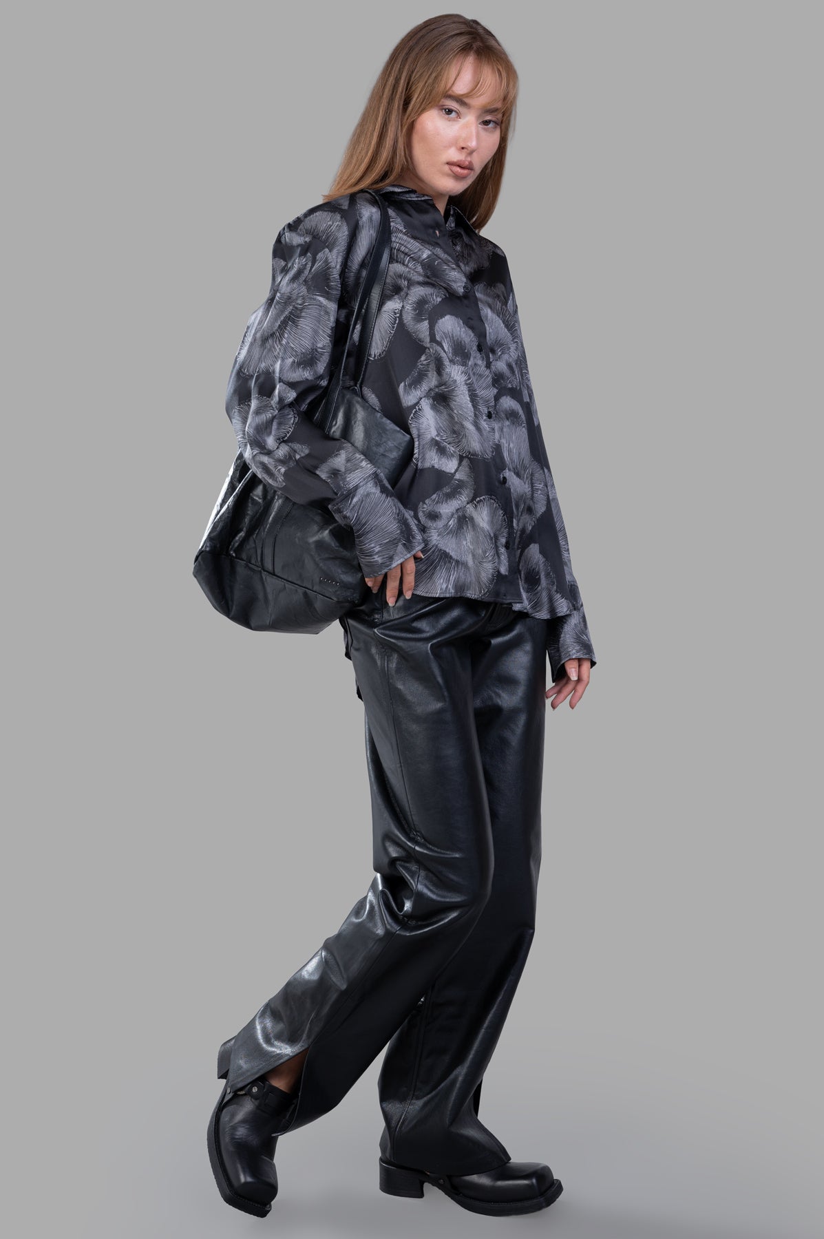 Anine Bing Avalon Shirt in black floral design, front view on model with leather pants and boots, carrying a black bag.