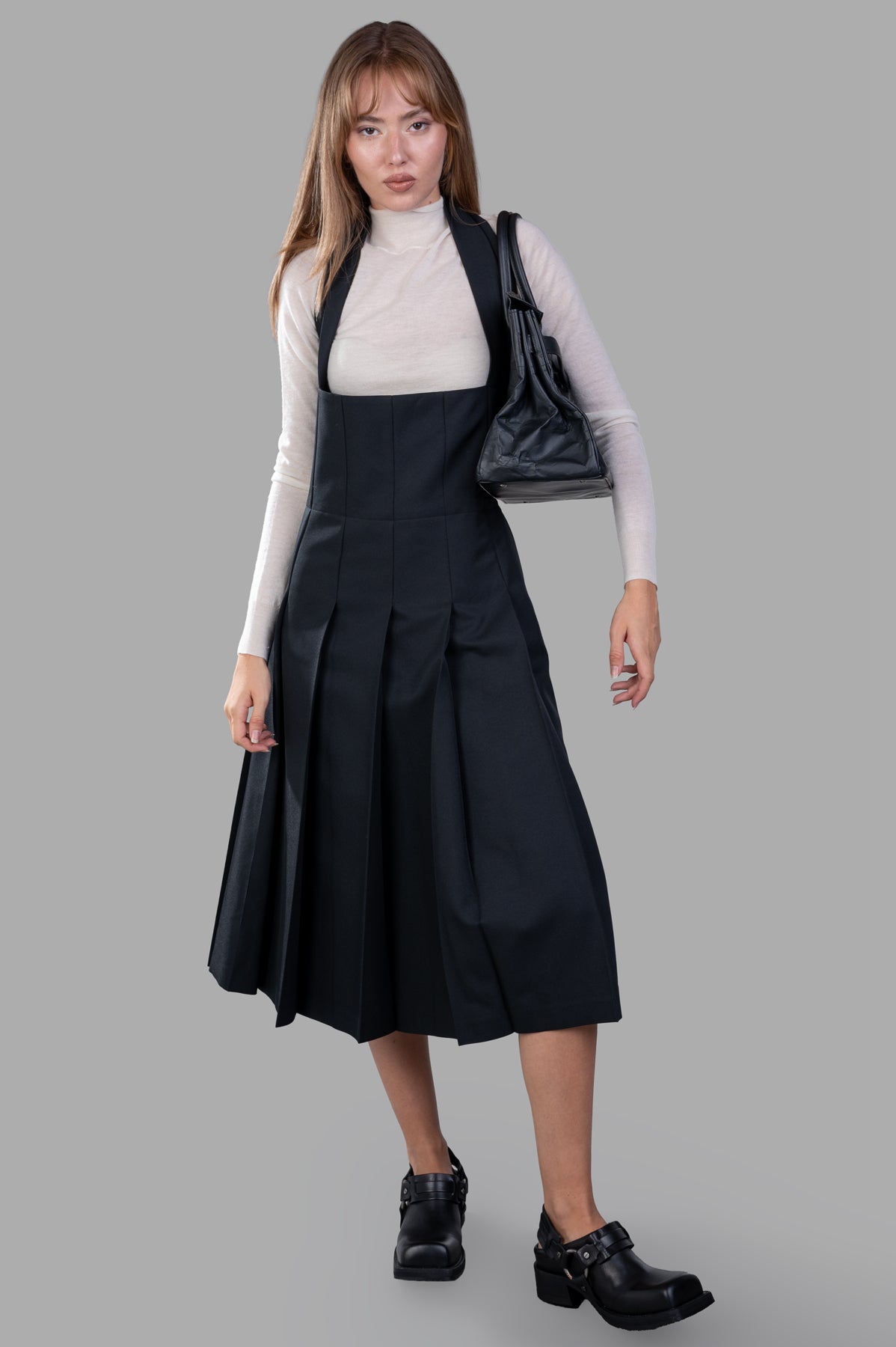 Comme des Garçons Pleated Suspender Dress in black, front view on model, showing A-line silhouette and halterneck design.