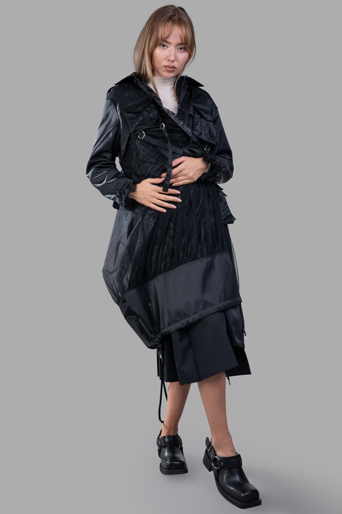 Noir Kei Ninomiya Reversible Trench Coat in black, front view showcasing button-fastening ruffle cuffs and D-ring straps.