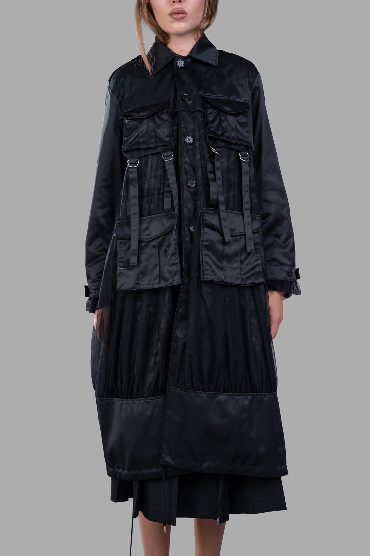 Noir Kei Ninomiya Reversible Trench Coat displayed on model, featuring button-fastening ruffle cuffs and multiple pockets.