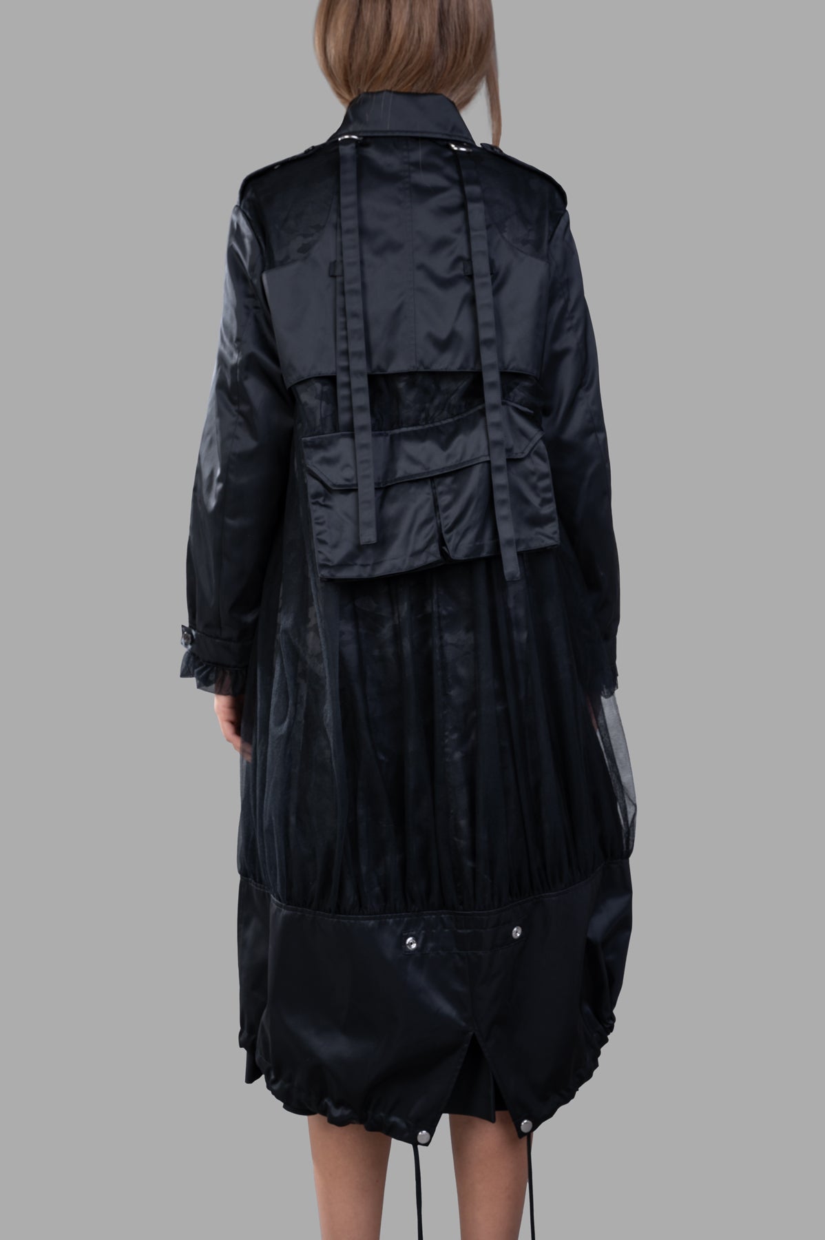 Noir Kei Ninomiya Reversible Trench Coat showing the back view with drawstring hem and elegant ruffle cuffs in black nylon.