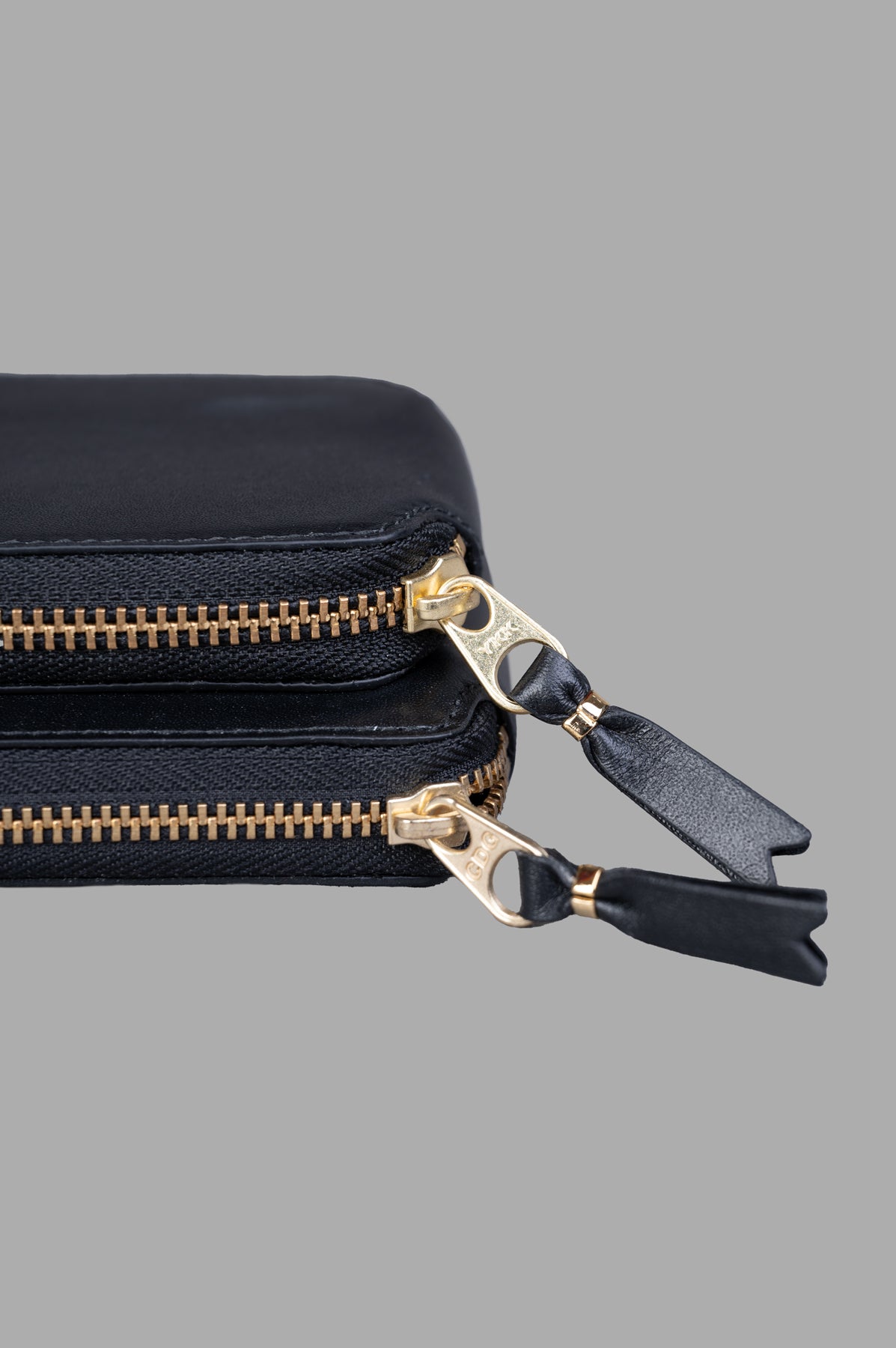 Comme des Garçons Double-Pocket Zip Wallet detail view showcasing dual zip closures and premium black leather texture.