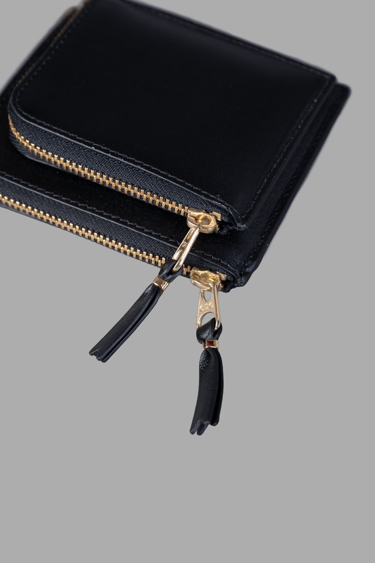 Comme des Garçons Small Double Wallet in black, showcasing gold zip closures and leather tassels for stylish access.