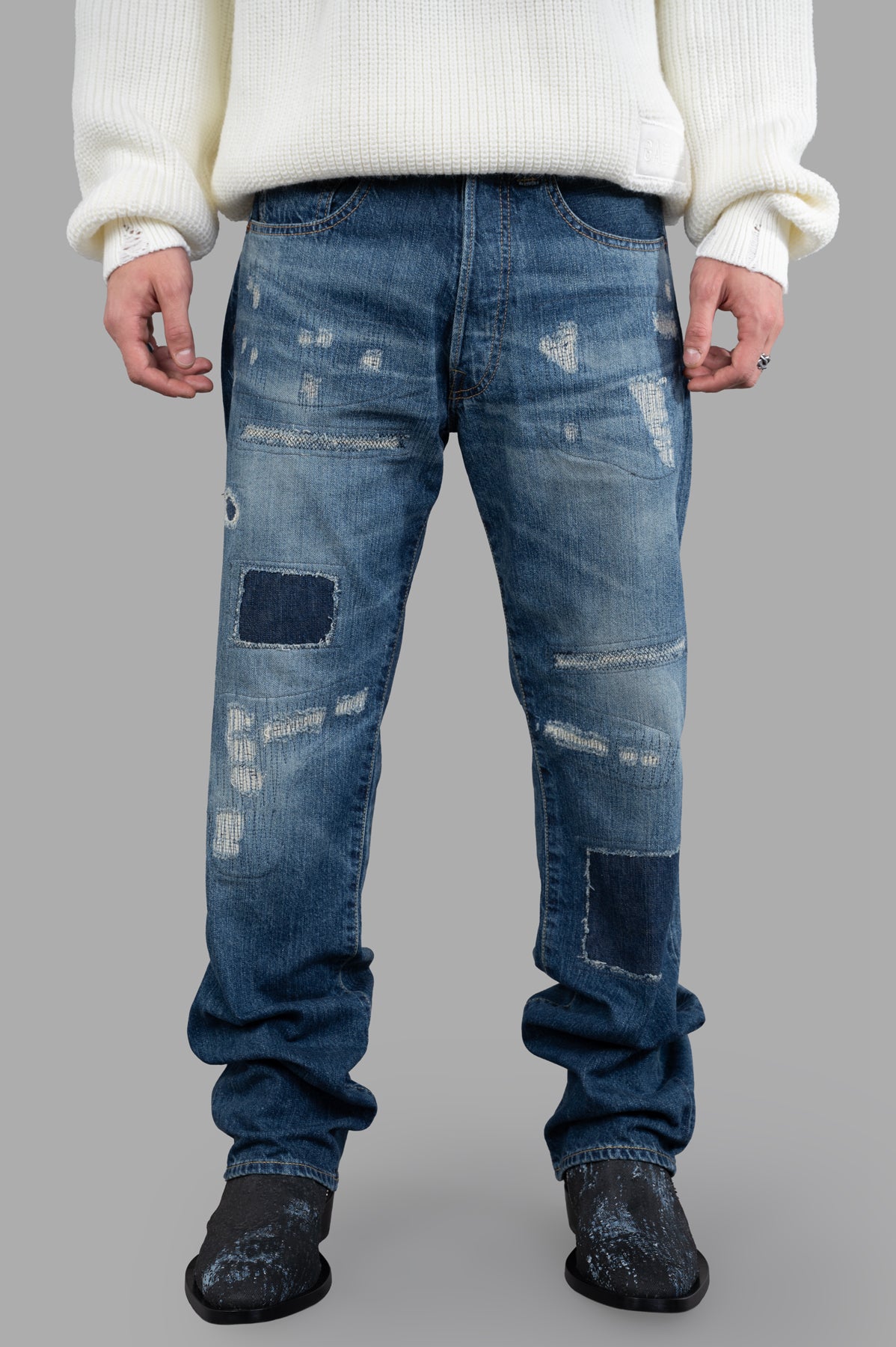 Junya Watanabe Indigo Distressed Jeans with patches shown from the front, featuring belt loops and five-pocket styling.