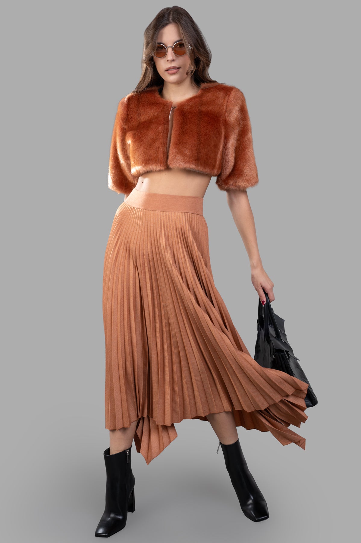 Alabama Muse Cropped Faux-fur Jacket in Visone, front view on a model, paired with a pleated skirt and boots.