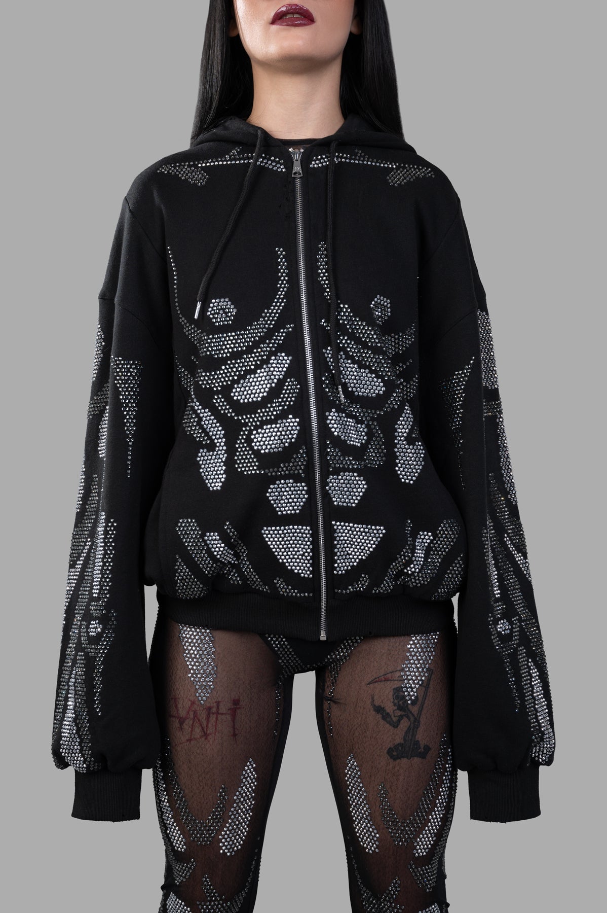 Natasha Zinko Rhinestone Embellished Hoodie with zip front and striking rhinestone detailing, displayed on a model.