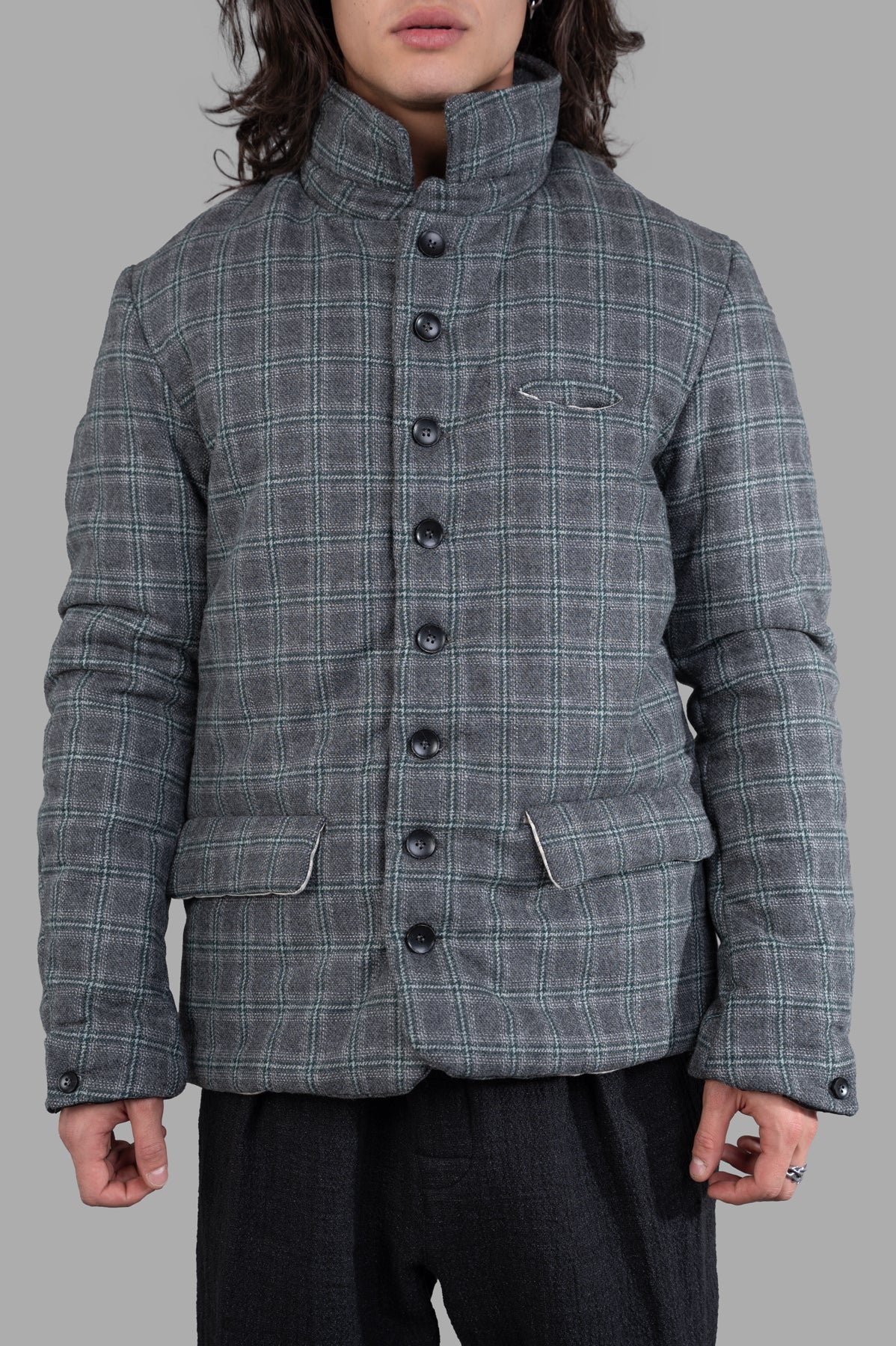 Model showcases a Marc Point plaid jacket with padding, highlighting its button-up design, sleek stand collar, and chic side.