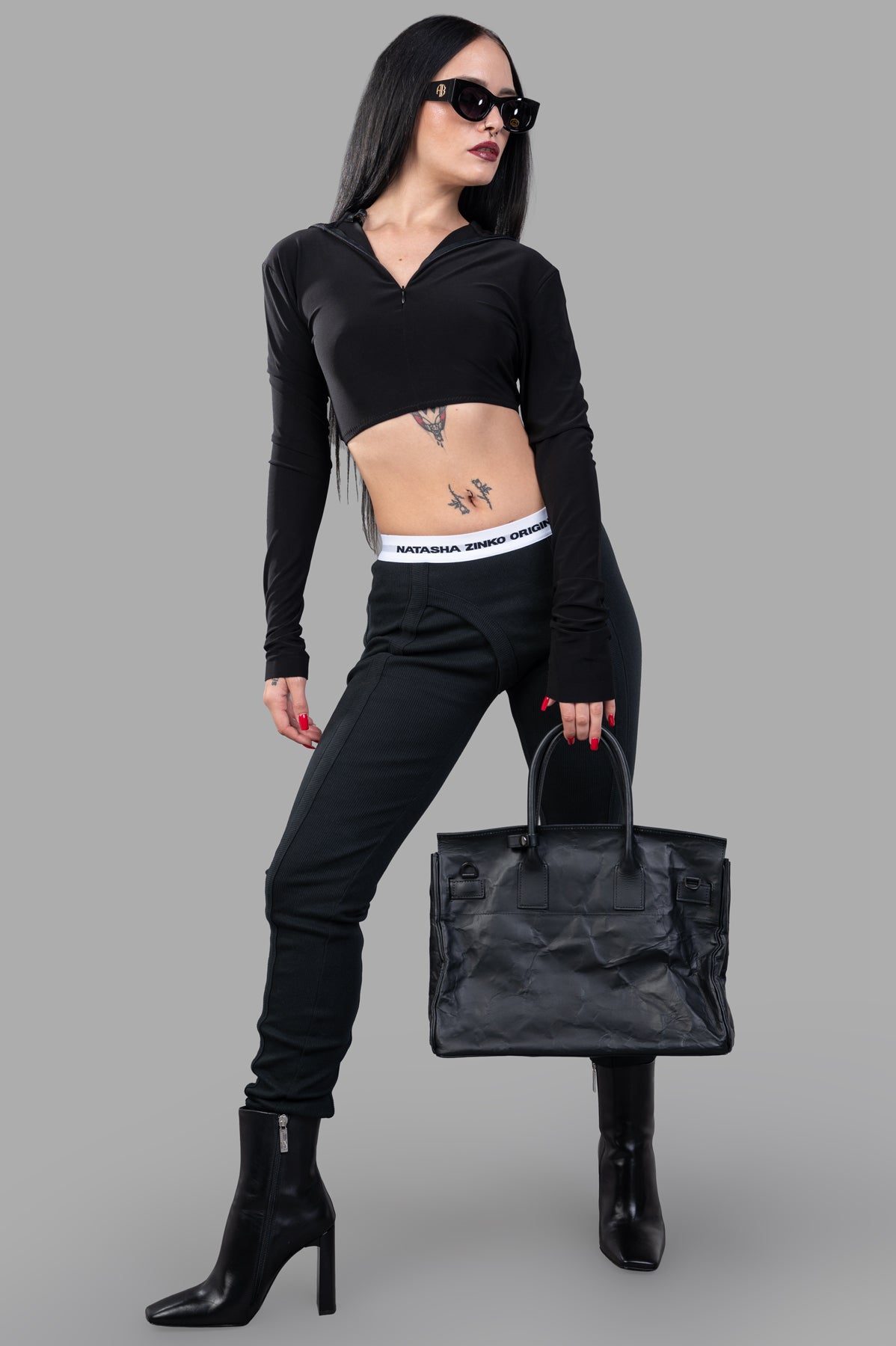 Natasha Zinko Jersey Leggings, black, on-model, front view. Features elasticated logo waistband and strap detail for style.