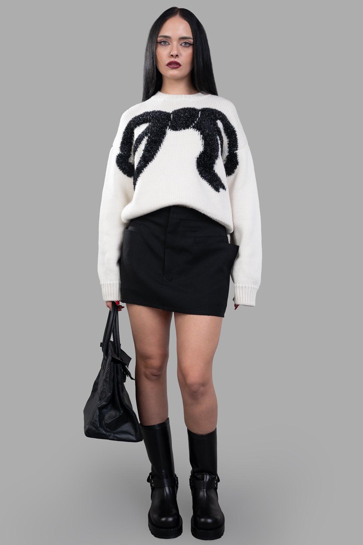 MSGM Bow Sweater, front view on model, featuring bold black bow design, paired with black skirt and boots. Image 1.