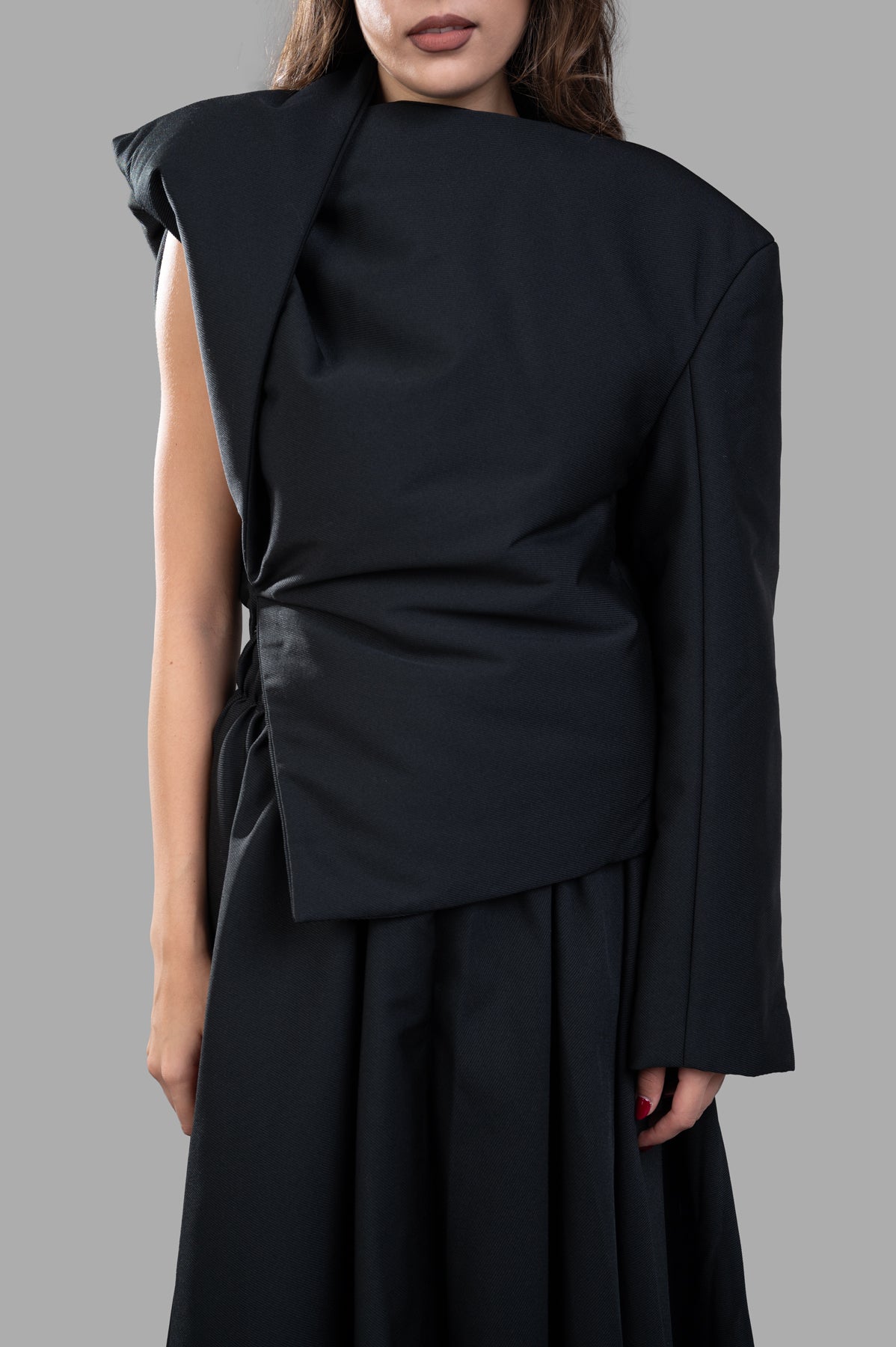 Uma Wang Padded Asymmetric Top in black, featuring unique design and cinched waistline, shown on model in close-up.