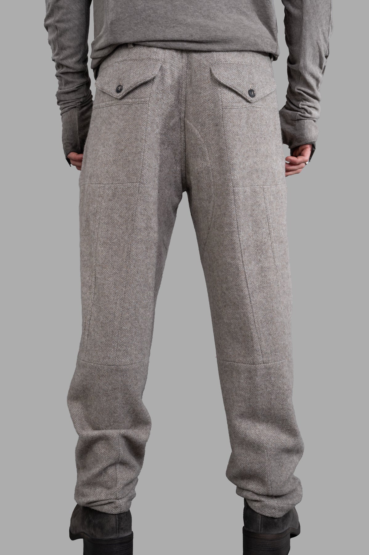 AION. Pleated Military Pants in beige, featuring a straight-leg cut and utilitarian back pockets, shown on model.