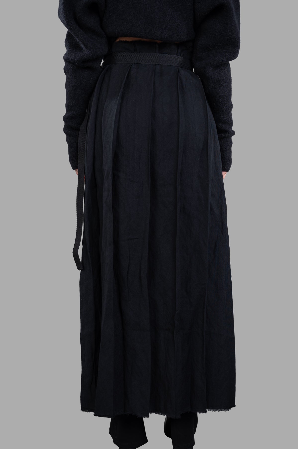 Masnada Pleated Maxi Skirt shown from the back, featuring a stylish silhouette with an elastic waistband and plush fabric.
