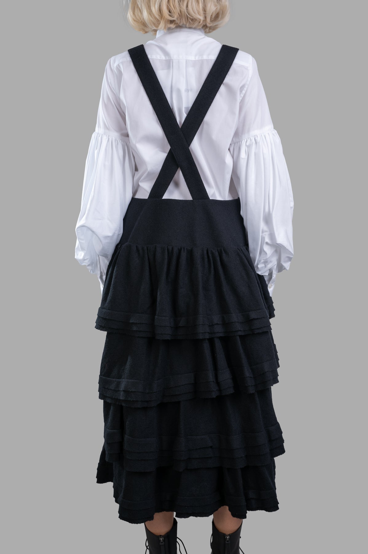 Noir Kei Ninomiya Wool Suspender Dress showcasing the layered ruffled tiers and adjustable straps from the back view.