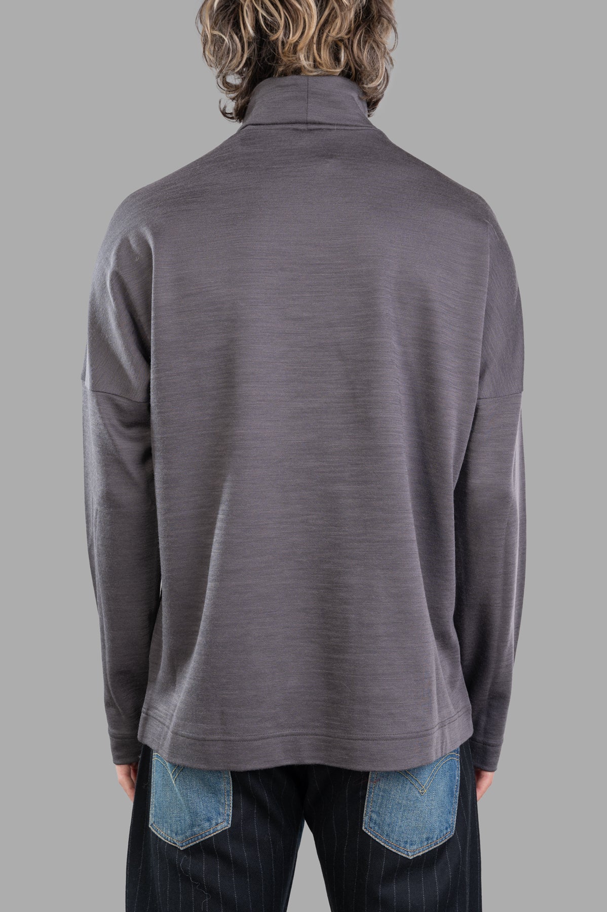 Attachment Turtleneck Top in grey, showcasing the back view, featuring a soft wool blend material and relaxed fit.