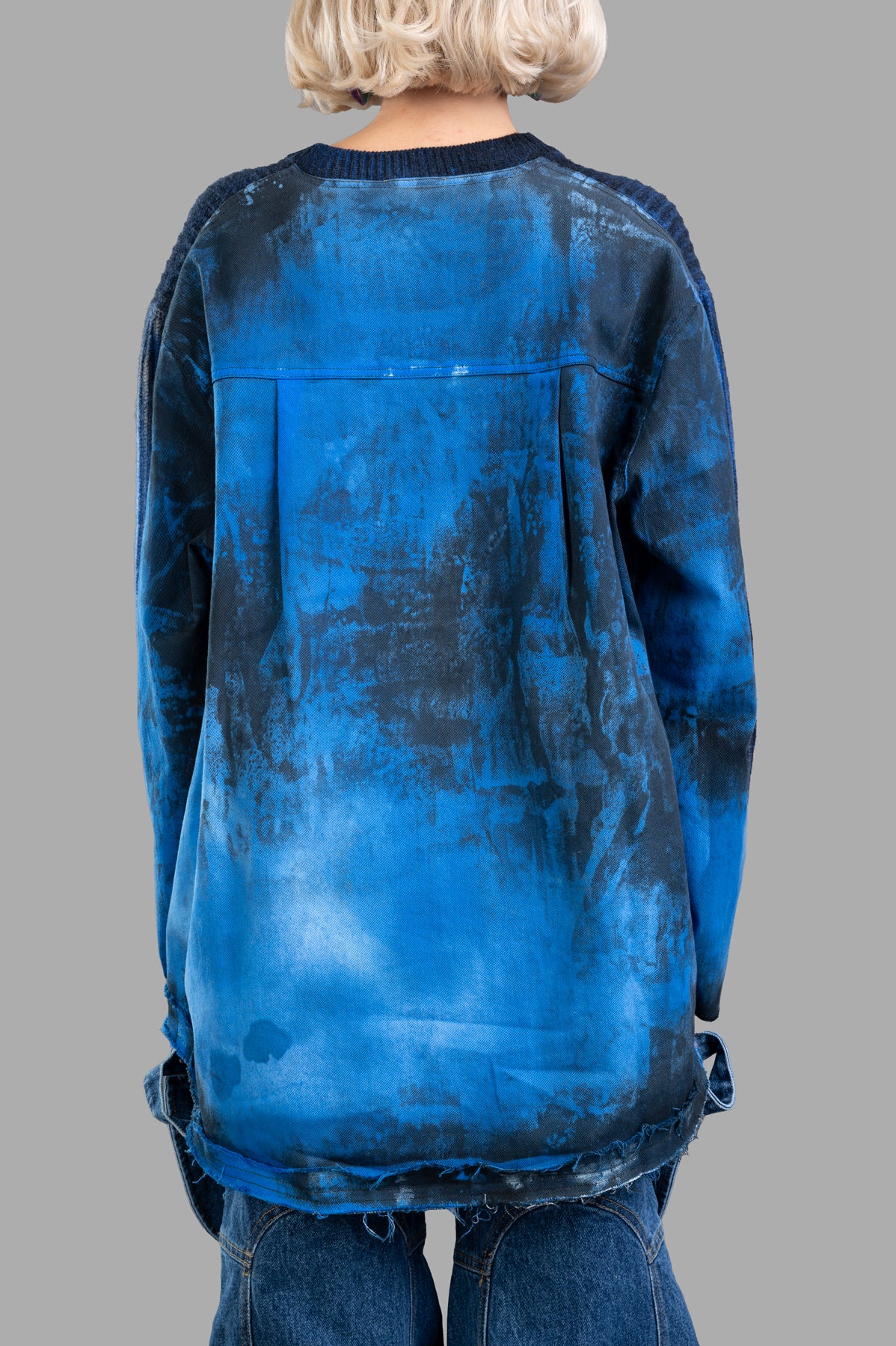 Avant Toi Faded-effect Sweater in blue, showcasing the oversized fit and asymmetric denim hem from the back view.