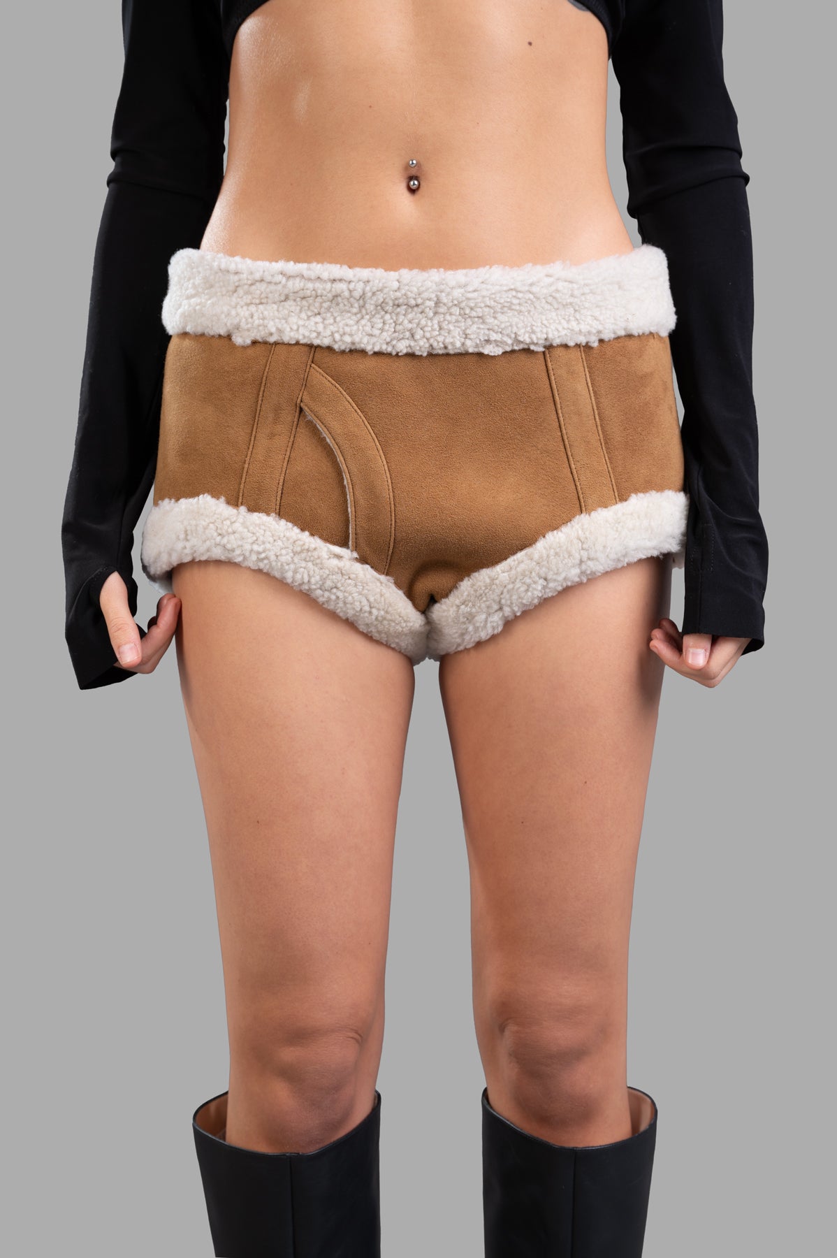 Natasha Zinko Sheepskin Mini Shorts in brown, featuring faux shearling trim, displayed on model from the front.