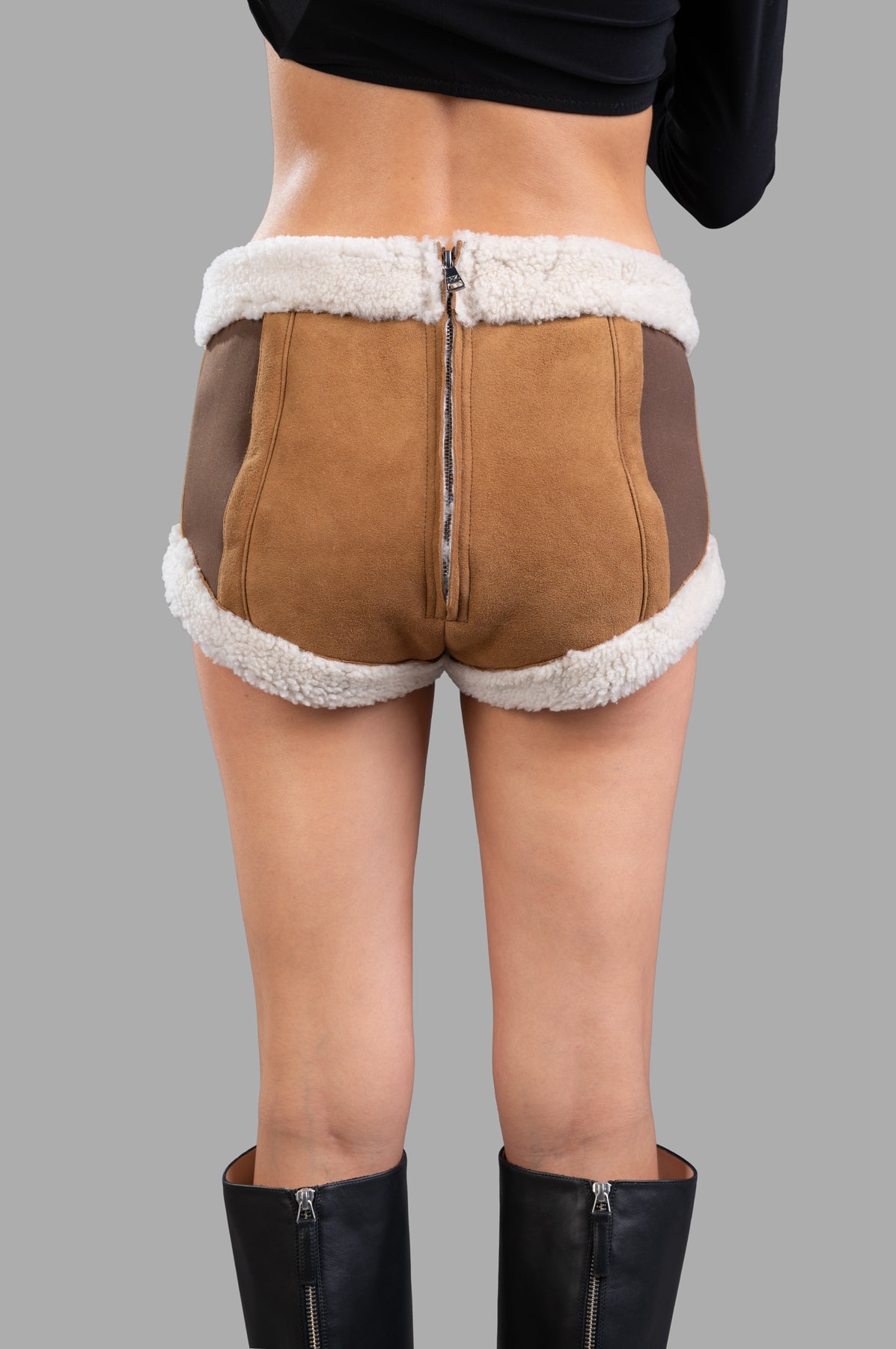 Natasha Zinko Sheepskin Mini Shorts featuring a cozy faux shearling trim, viewed from the back, showcasing rich brown.