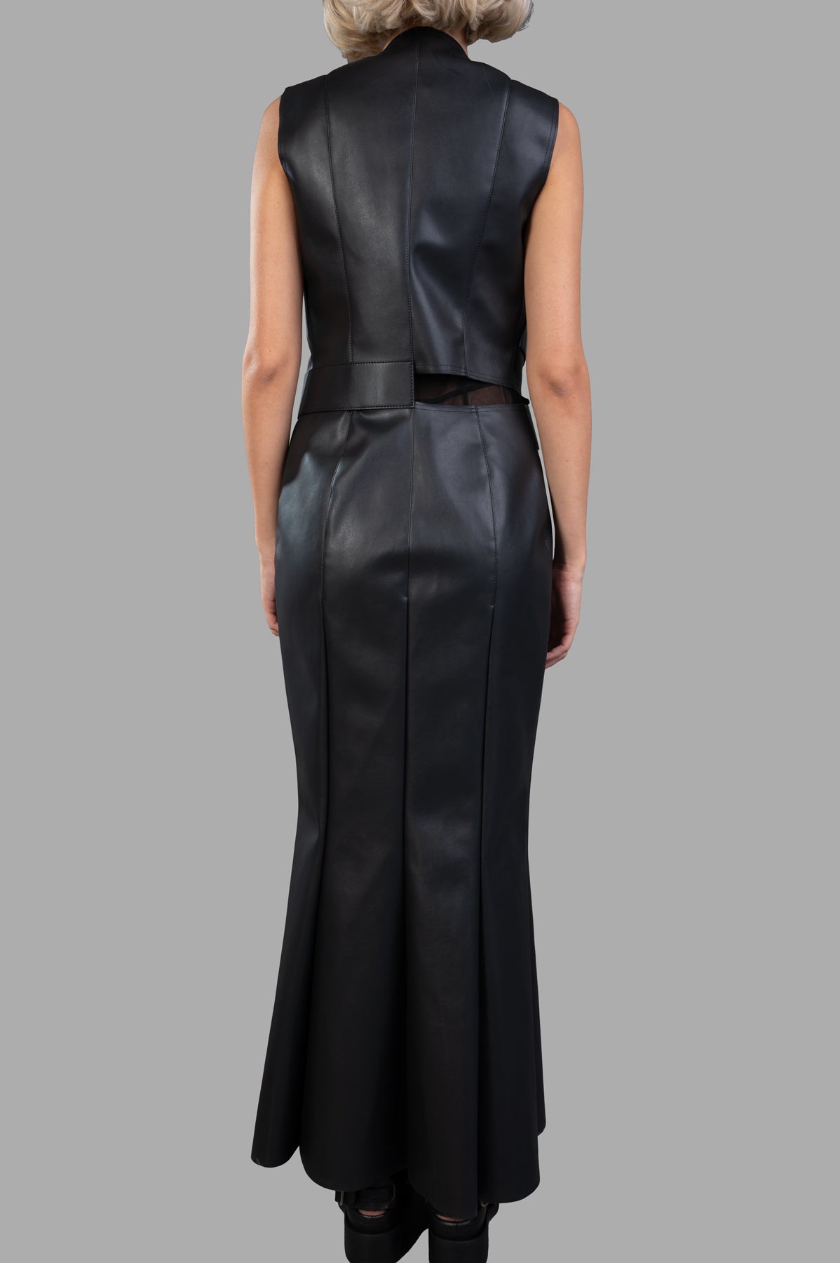 Junya Watanabe Faux Leather Dress displayed from the back, featuring a sleek paneled silhouette in black synthetic leather.