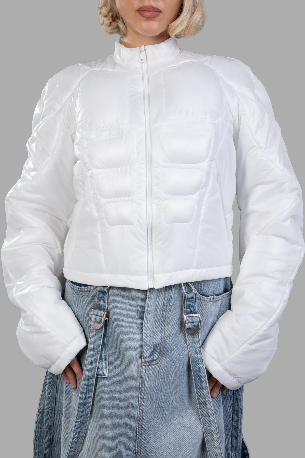 Natasha Zinko Muscle Puffer Jacket in white, featuring a padded design, mock neck, and zip closure, shown on model.