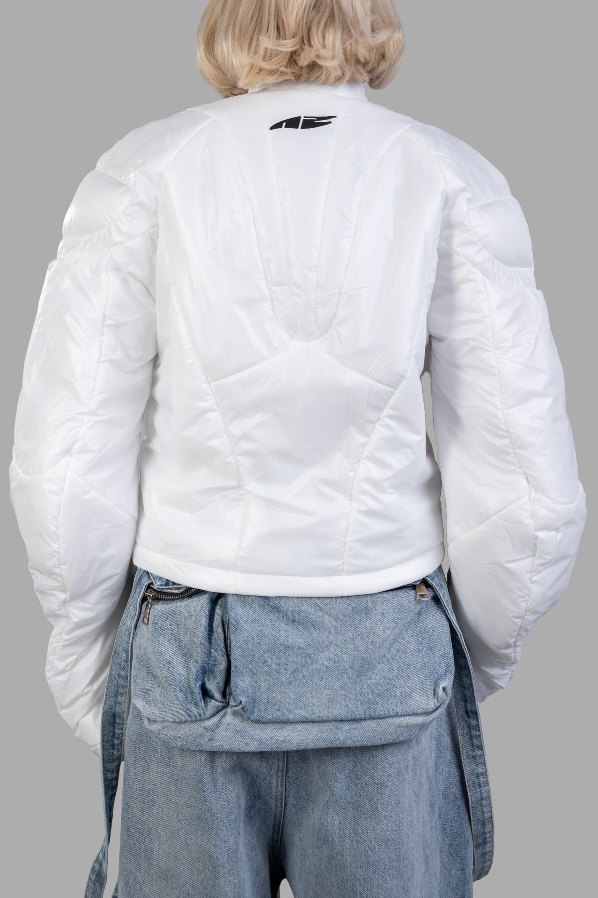 Natasha Zinko Muscle Puffer Jacket showcasing a cozy padded back, mock neck, and stylish quilted design in white.
