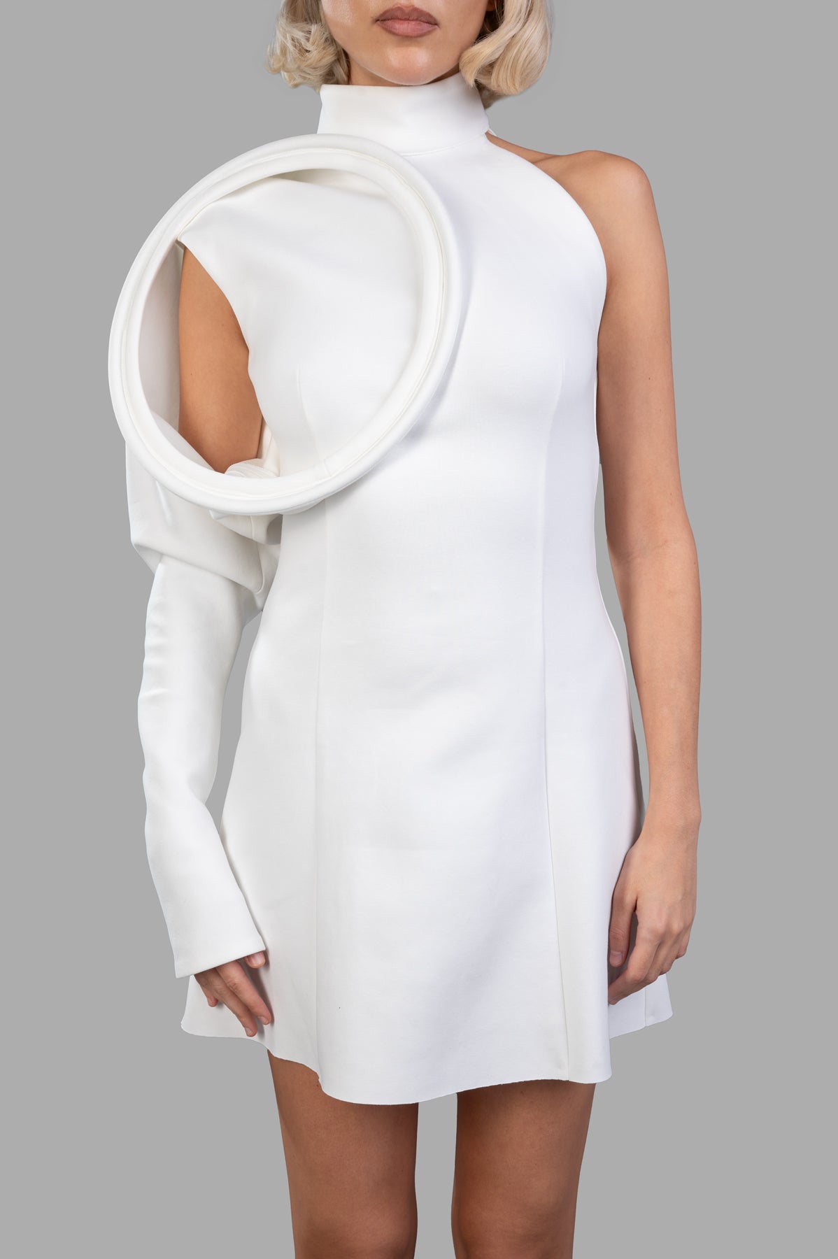 Natasha Zinko 60s-inspired Dress, front on-model: white mini, high neck, one sleeve with large circular shoulder detail.