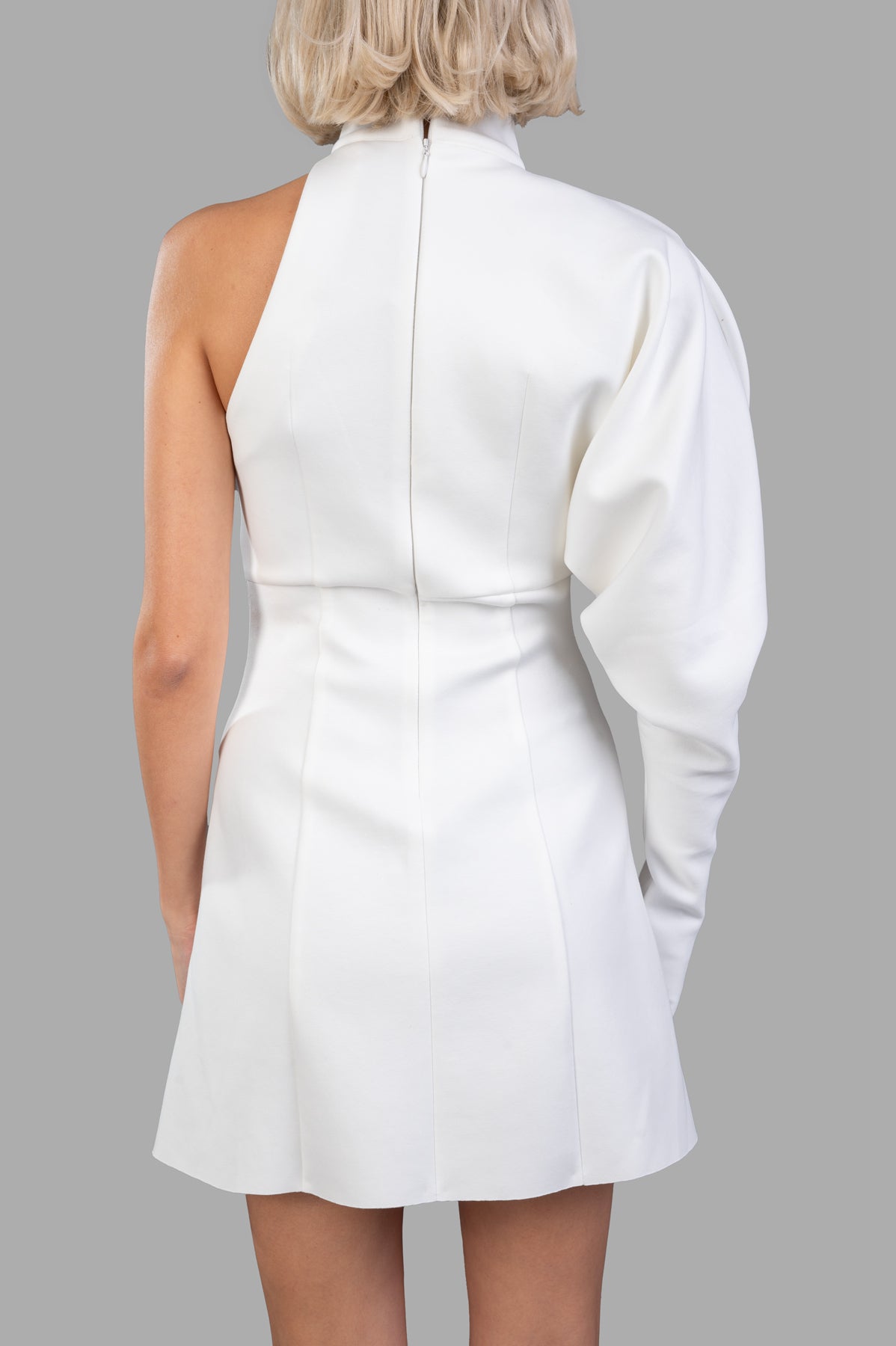 Natasha Zinko 60s-inspired Dress, back view on-model showing white mini with one long puff sleeve, halter neck and back zip.