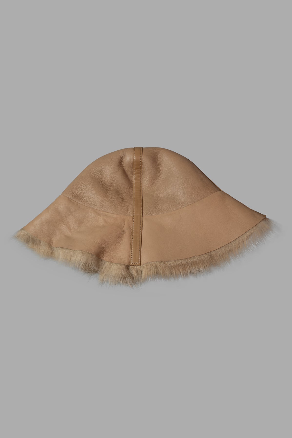By Malene Birger Reversible Leather Bucket Hat in beige, side view with shearling trim detail.