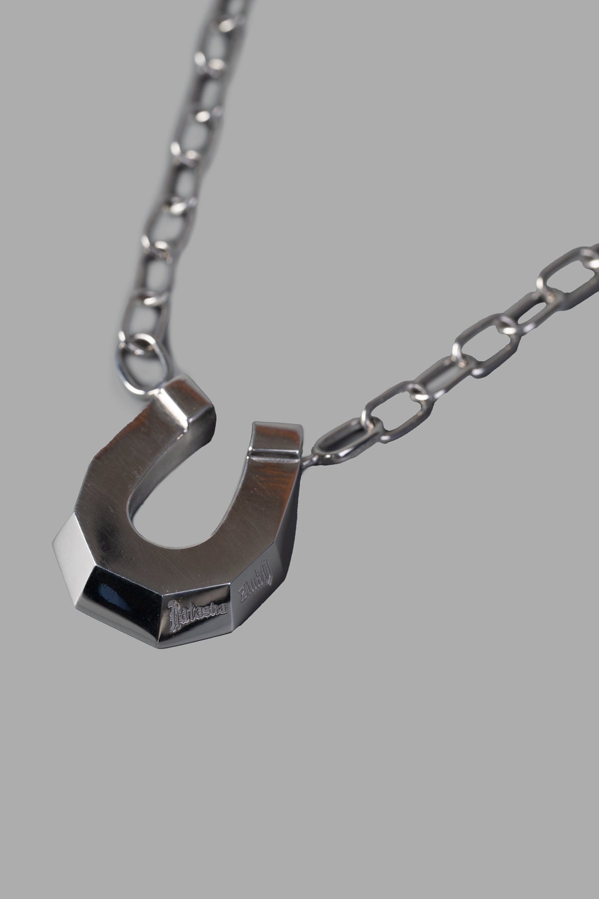 Natasha Zinko Horseshoe Necklace features a chunky silver logo-engraved pendant on a sleek chain, showcasing exquisite.