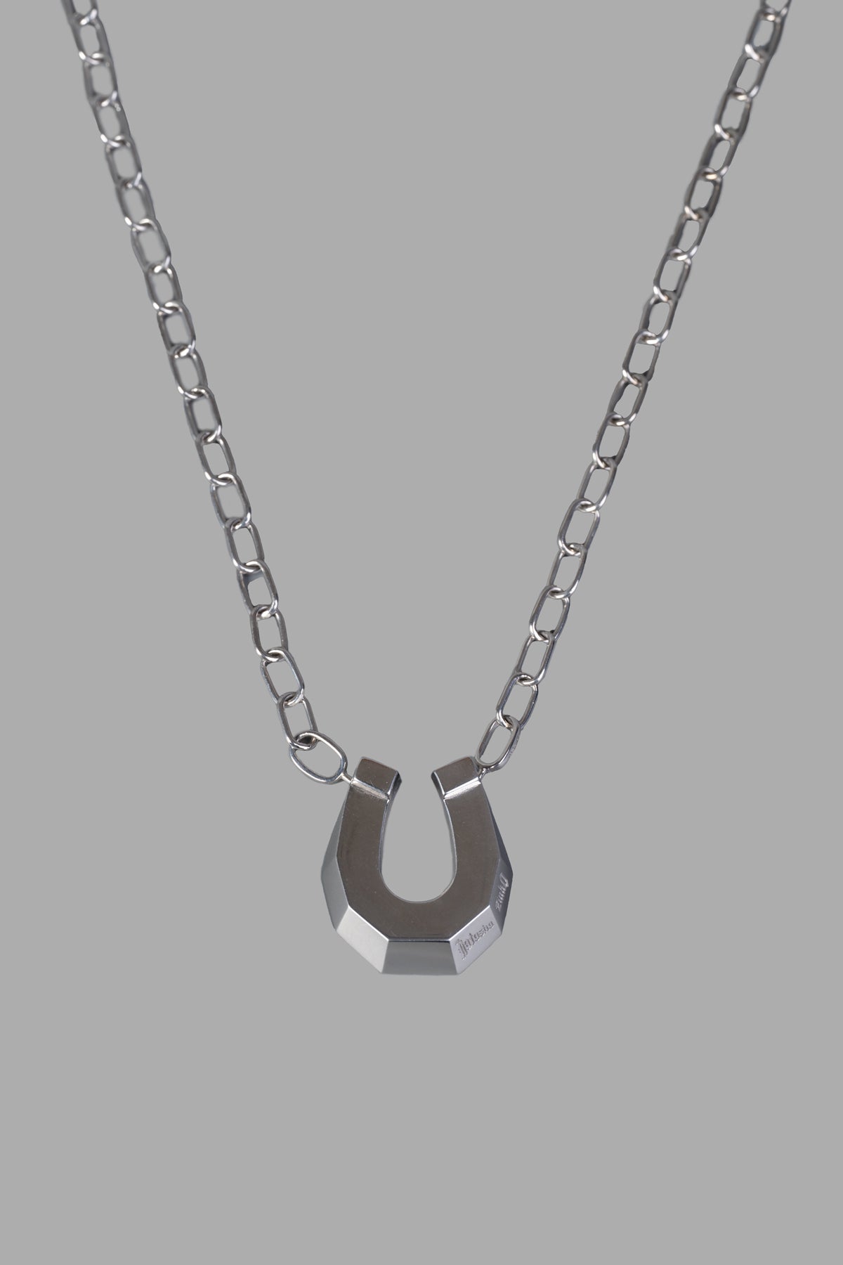 Natasha Zinko's Horseshoe Necklace presents a bold silver pendant on a contemporary chain, highlighting its intricate design.
