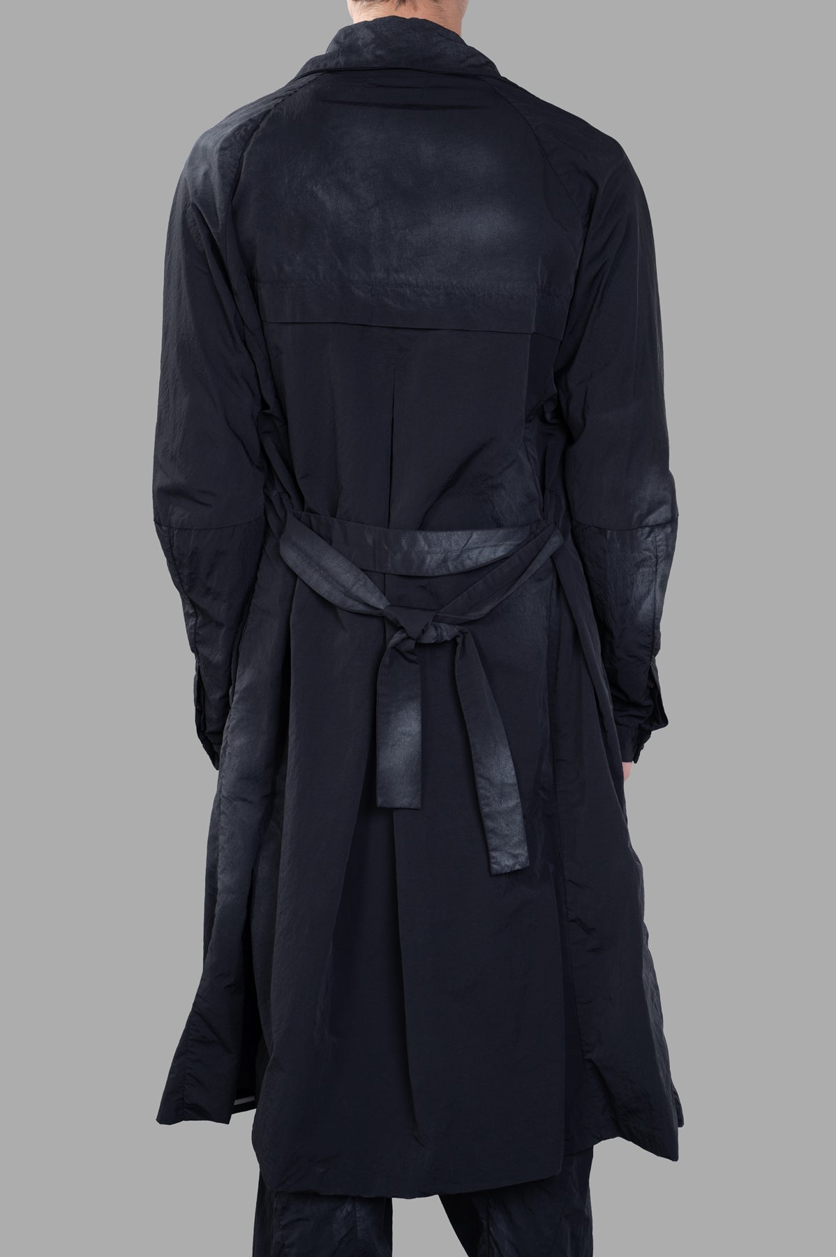 Marc Point Double-breasted Trench shown from the back, featuring a belt and unique faded-effect pattern in black.