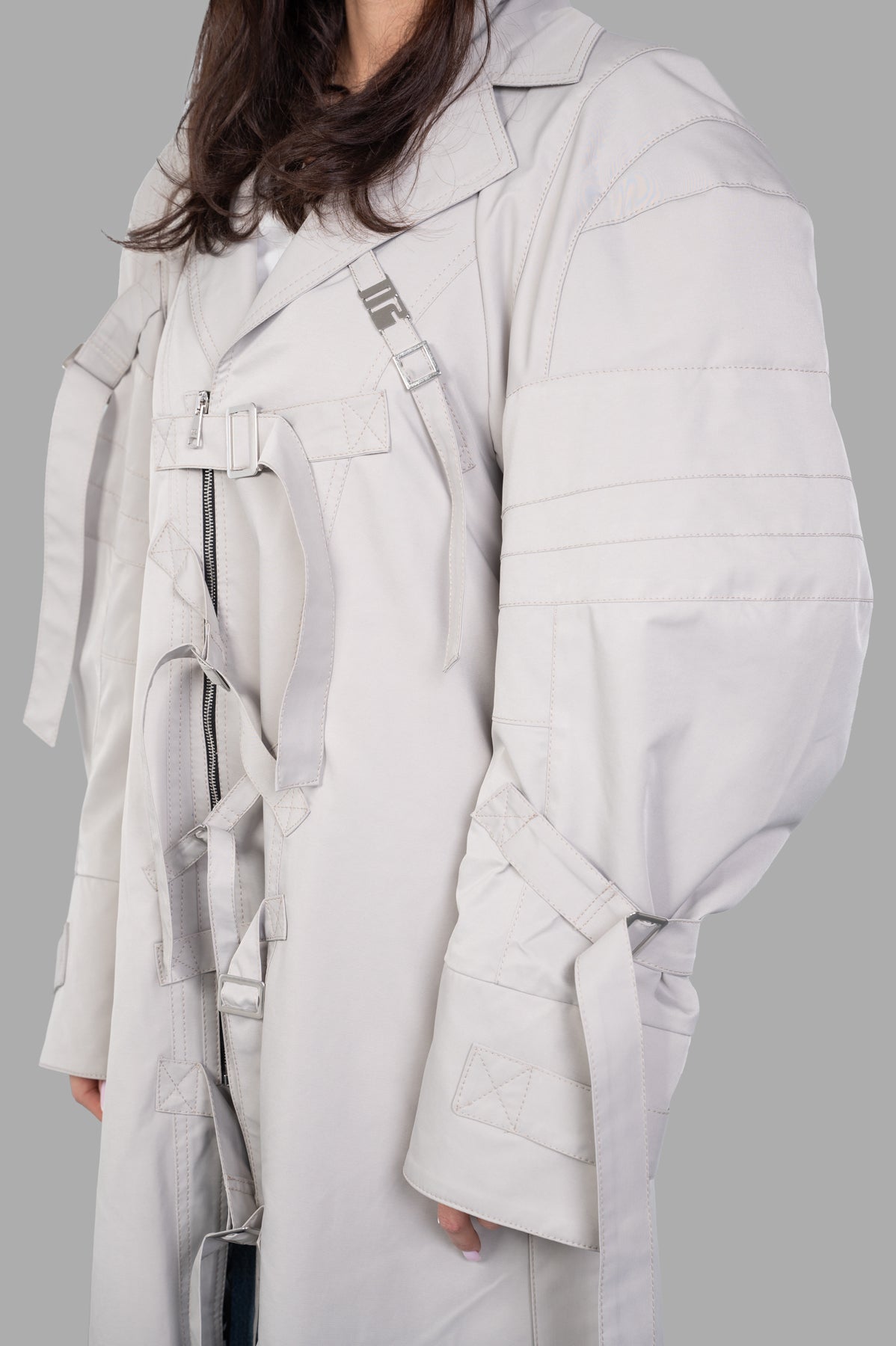 Natasha Zinko Strapped Trench showcasing sleeve straps, double-breasted zip, and tonal stitching in oversized fit.