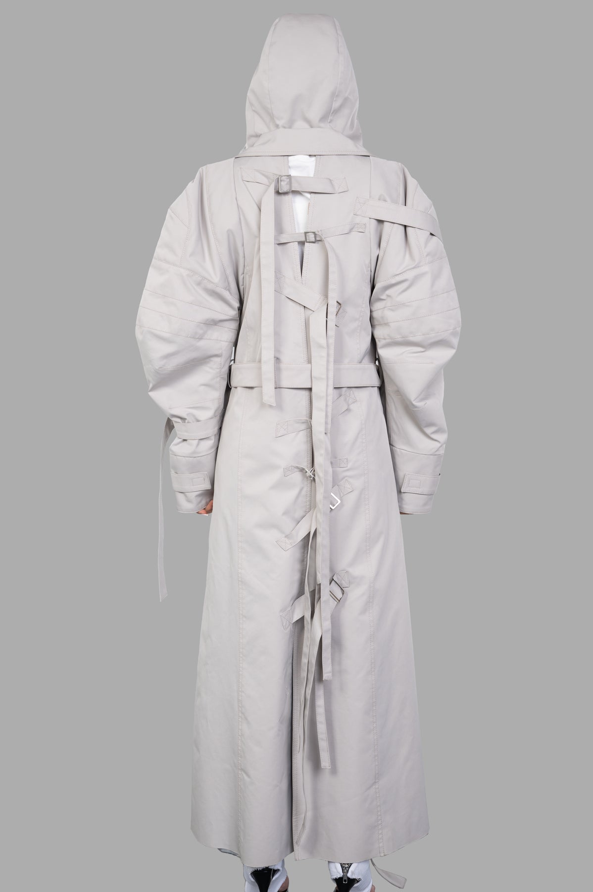 Natasha Zinko Strapped Trench features a hood and cinch straps, showcasing its oversized fit and panelled cotton design.