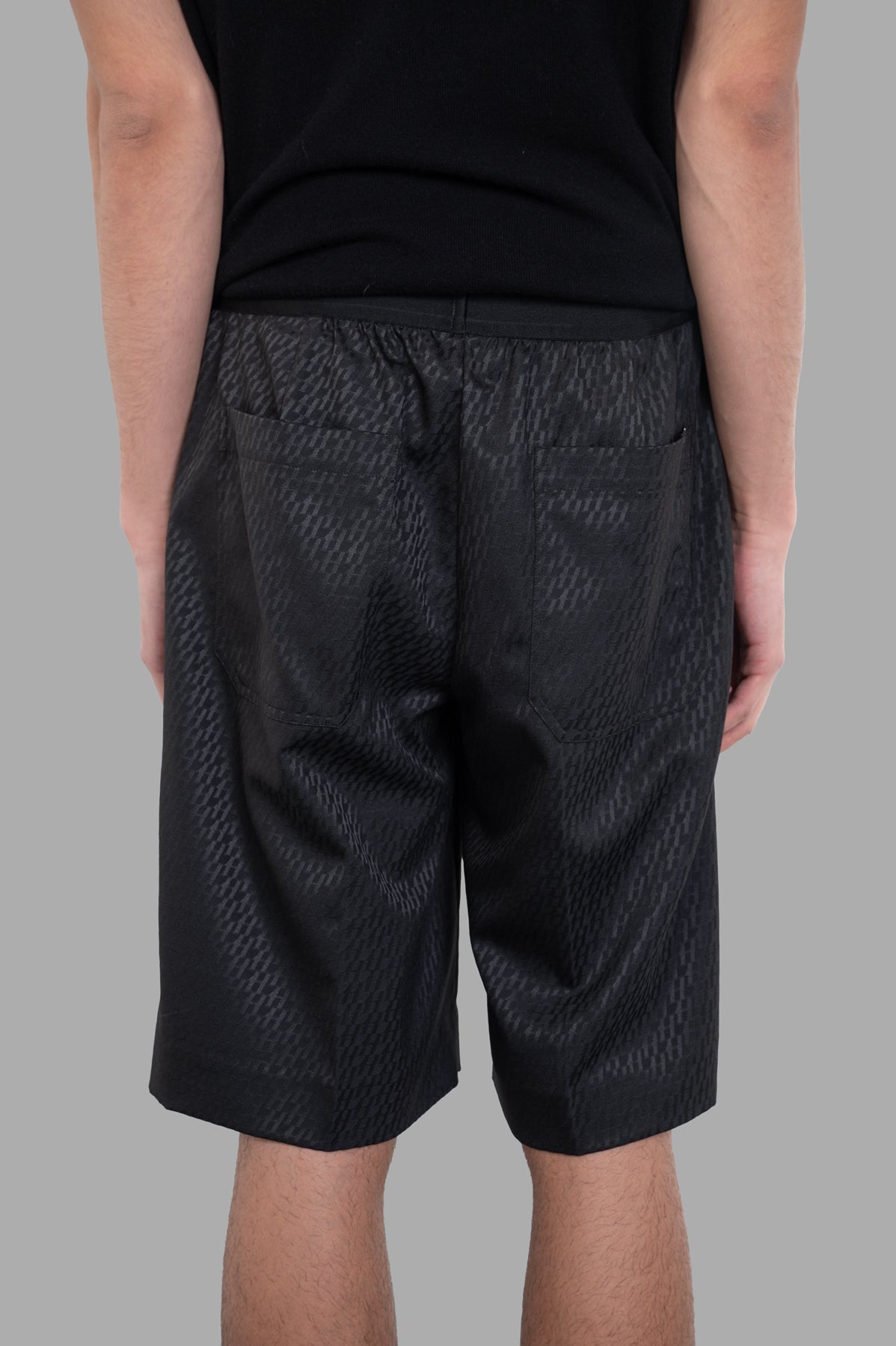 Helmut Lang Jacquard Car Shorts showcasing a sleek black satin finish and hidden pockets, viewed from the back.